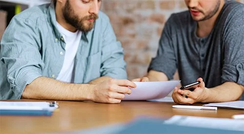 Two people reviewing business insurance paperwork with workers compensation