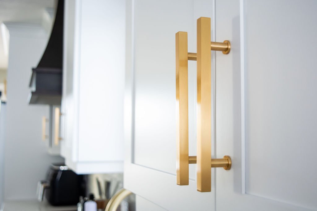 Close-up of a white kitchen cabinet with gold handles in a modern kitchen.