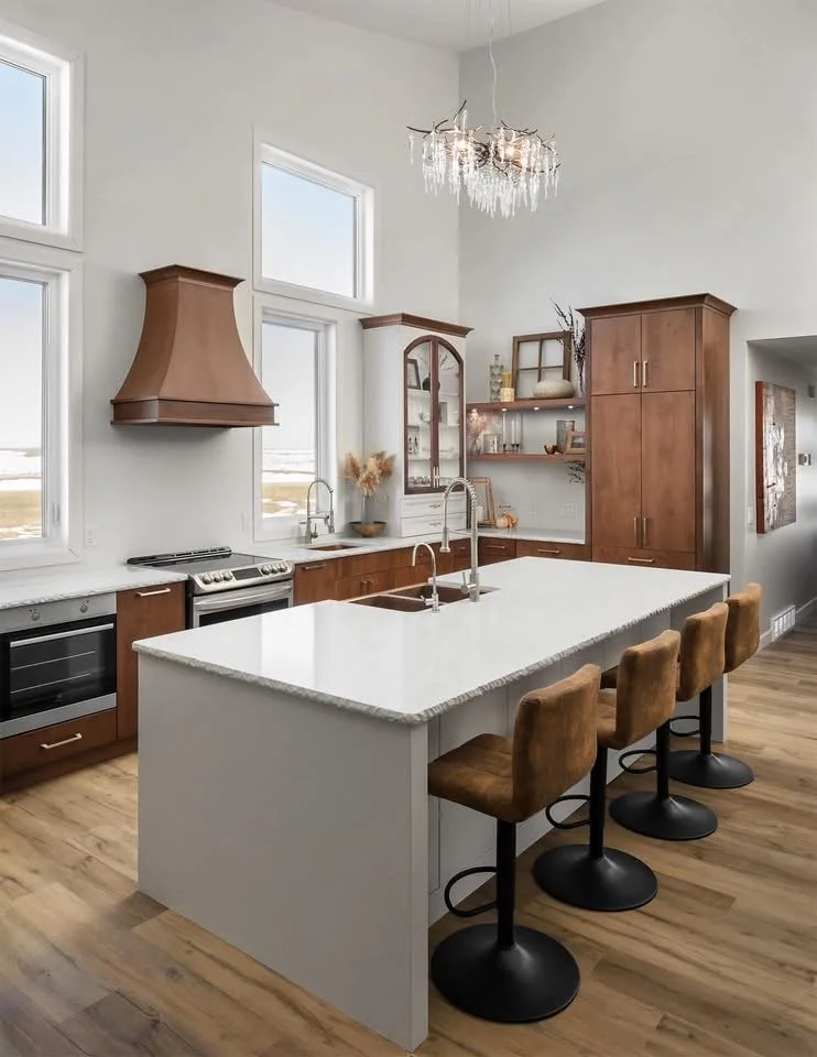 Modern kitchen with white island, brown bar stools, wooden cabinets, granite countertops, and large windows letting in natural light.