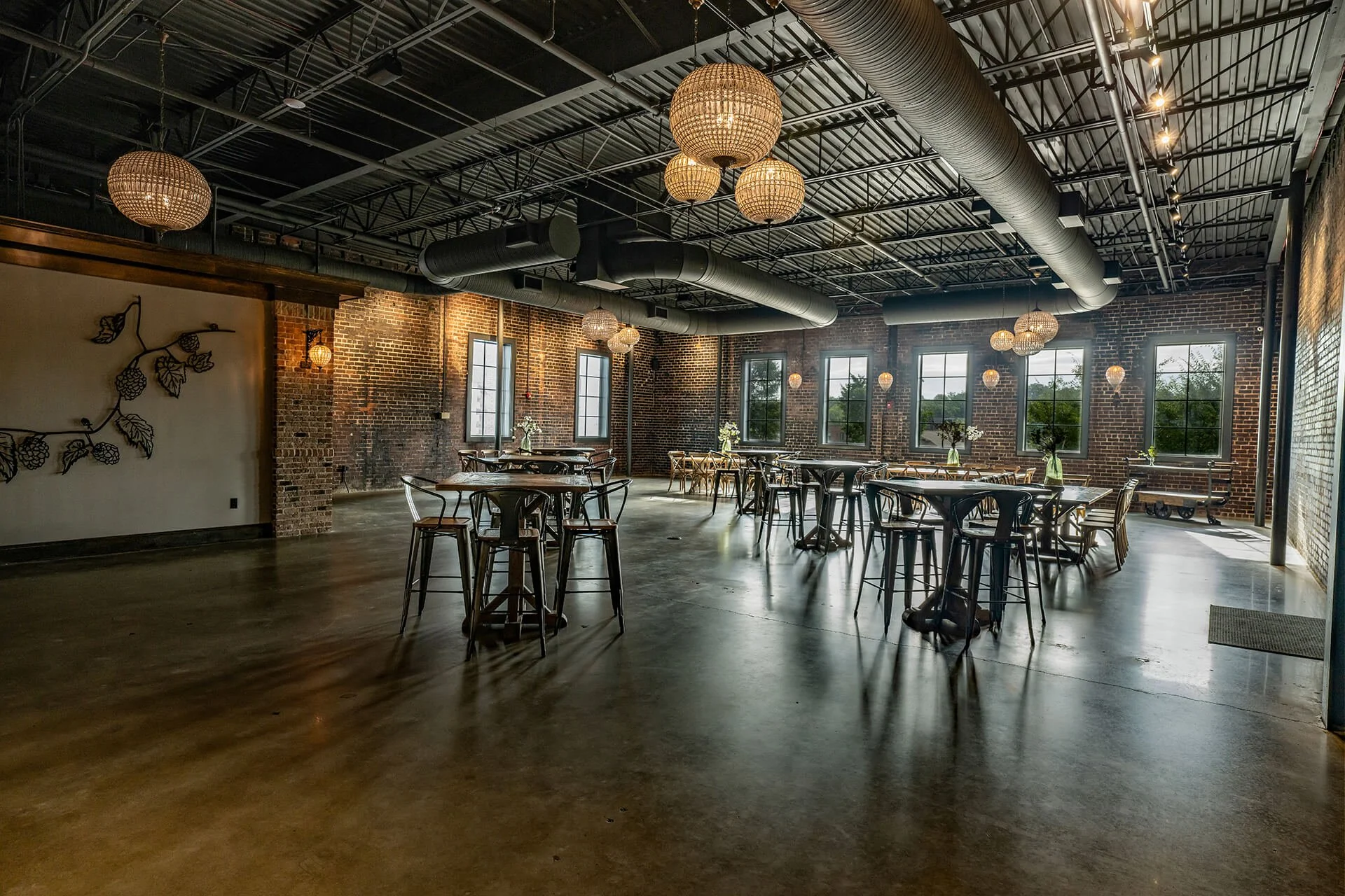  Spacious industrial-style venue with brick walls, modern lighting, and rustic wooden tables, designed for events and gatherings. 