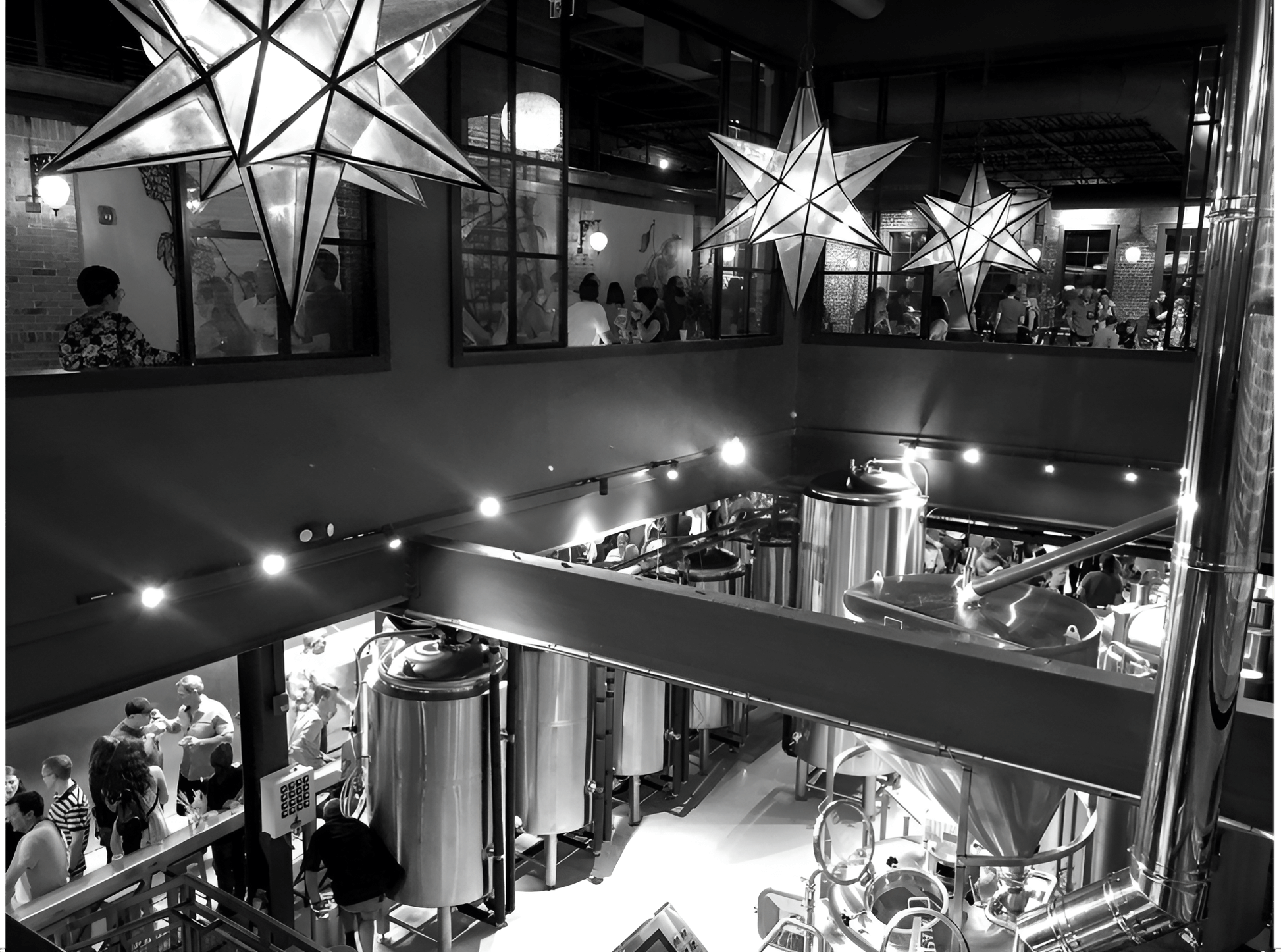 Black and white image of a two-story brewery and event venue. An event is being hosted on the upper level.