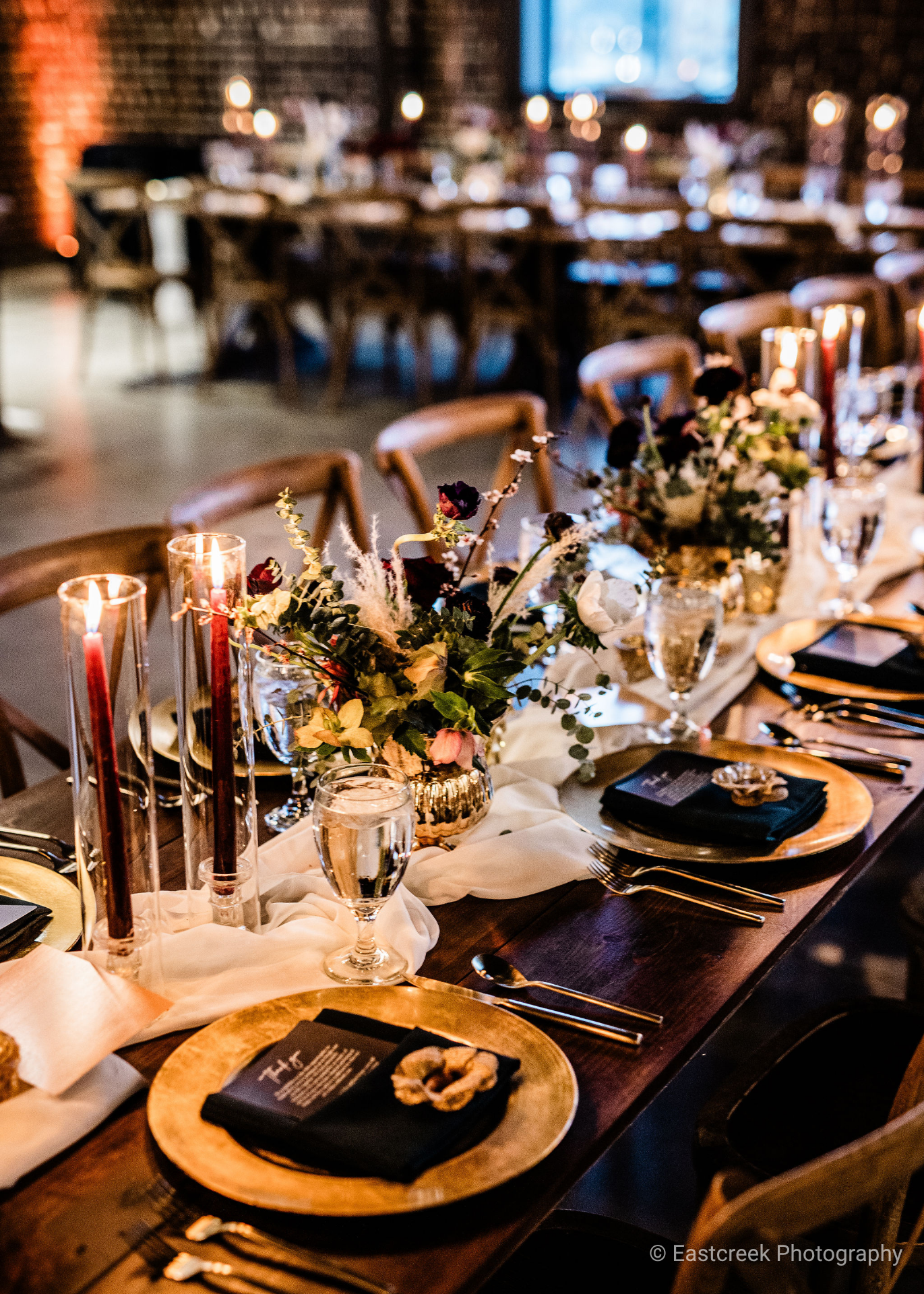 photo of long tables with wedding-style place settings and bouquets in the center of the table