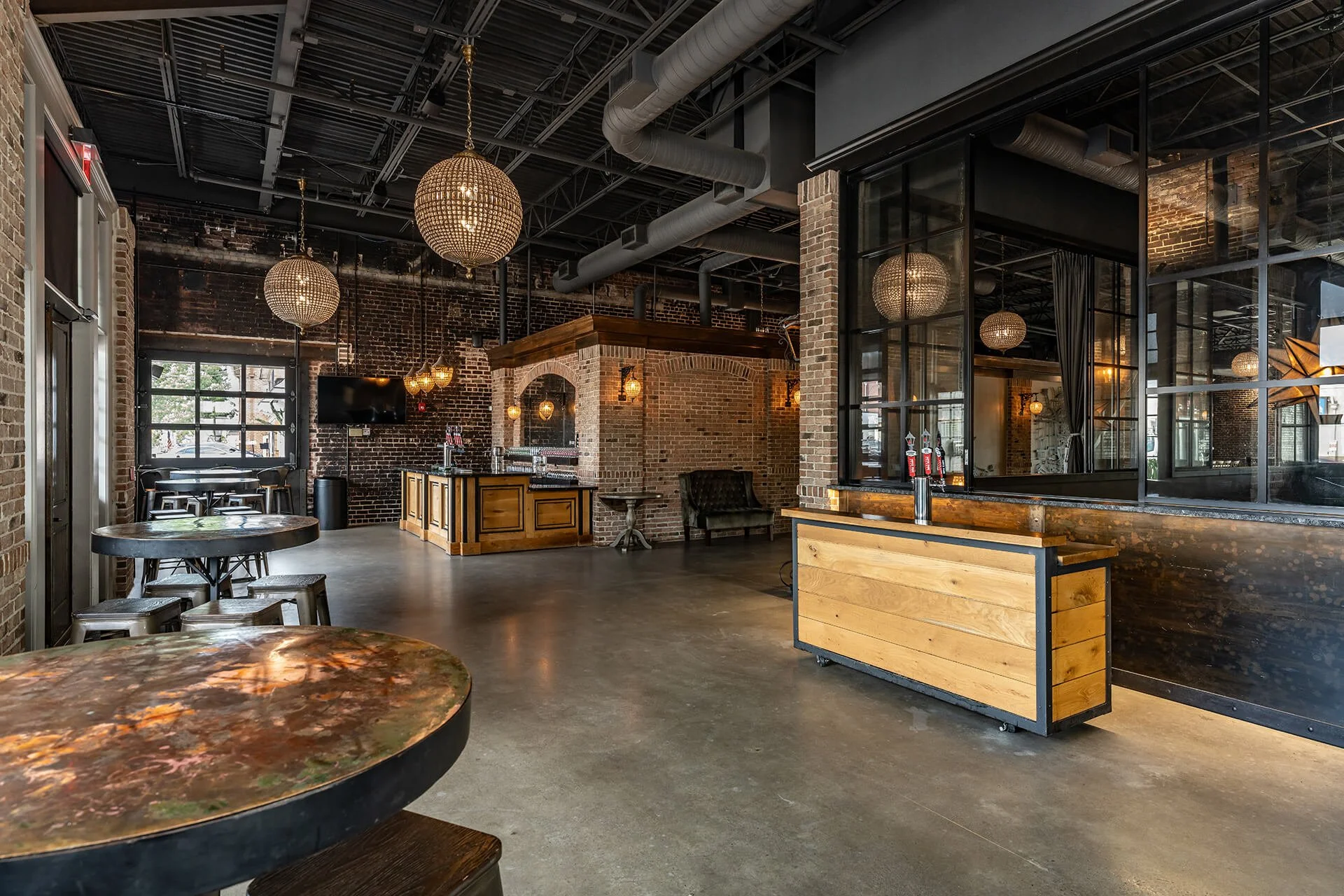 Stylish interior featuring exposed brick walls, modern chandeliers, and a sleek bar with wooden accents in a spacious, inviting atmosphere. 