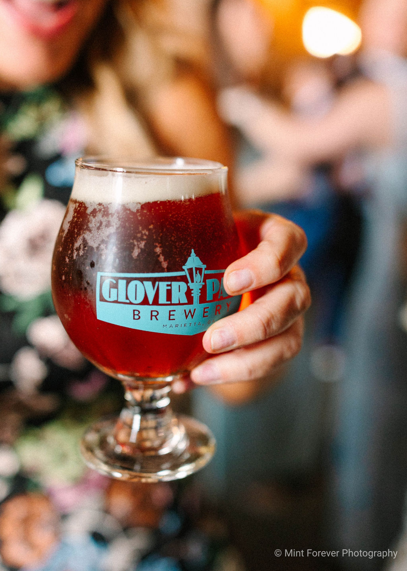close up of hand holding glass full of beer with etched Glover Park Brewery logo