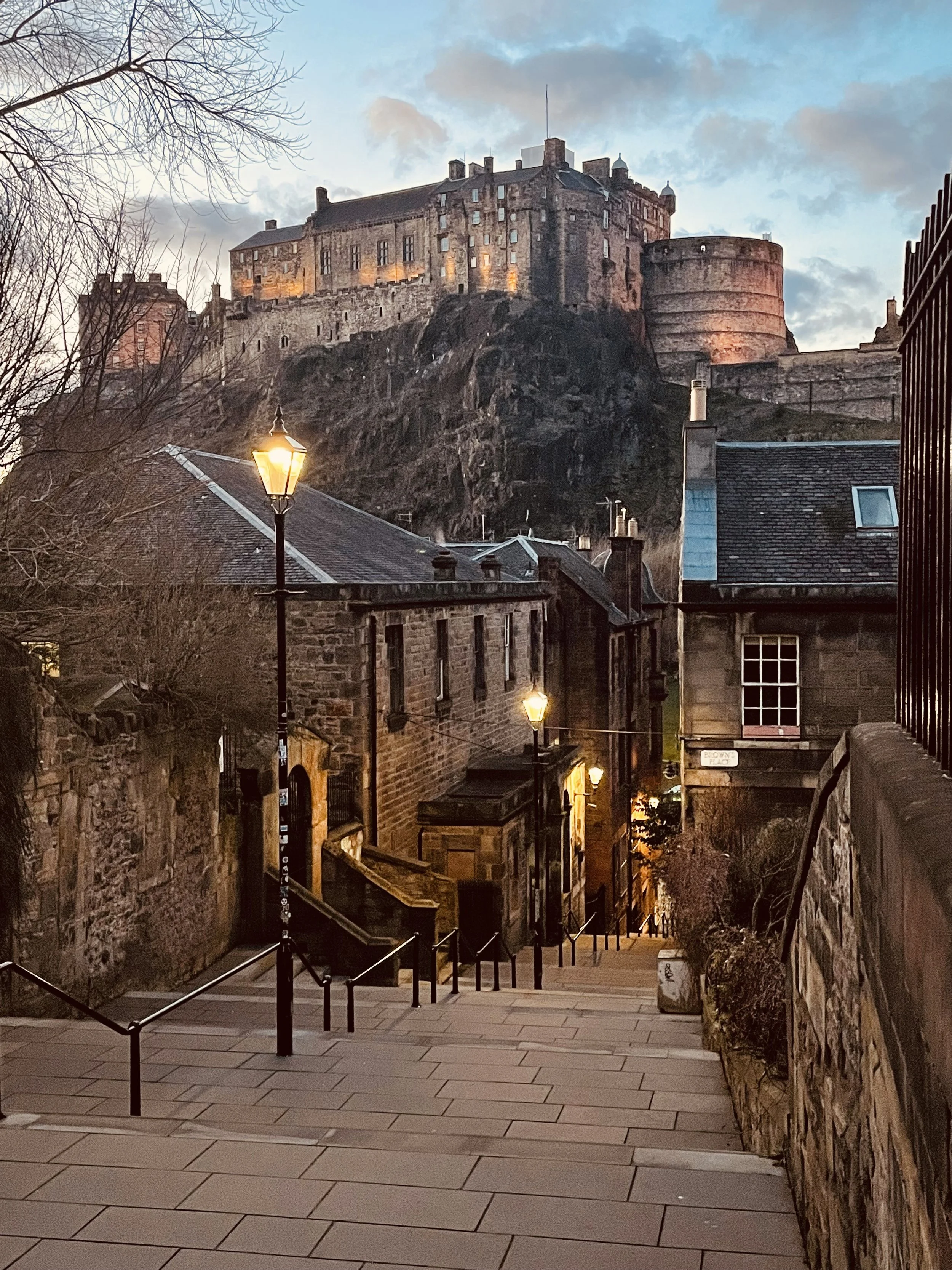 view of edinburgh castle from the vennel at dusk, with gas lamps on