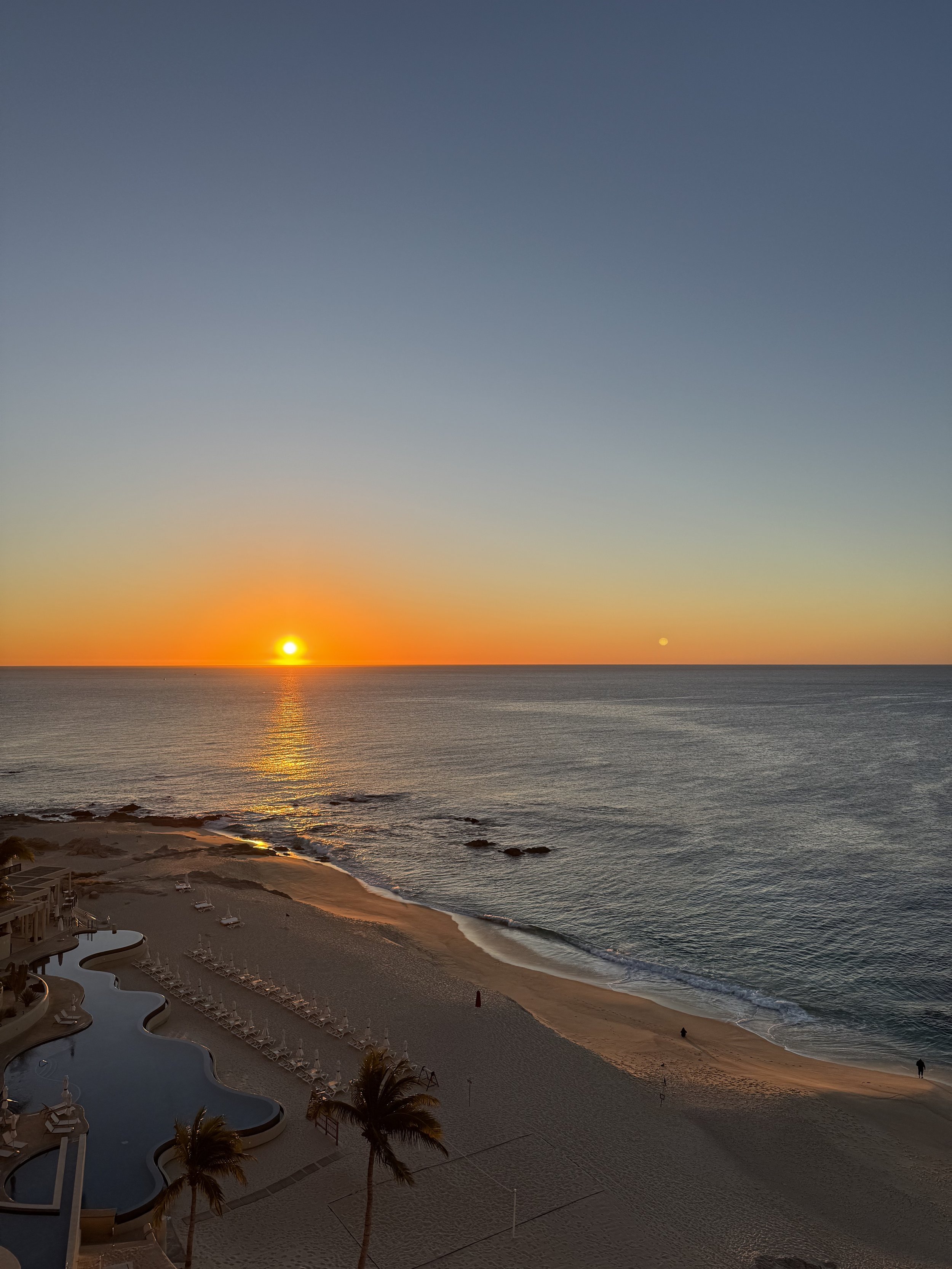 a bright orange sunrise over the sea of cortez with the westin pool in the foreground