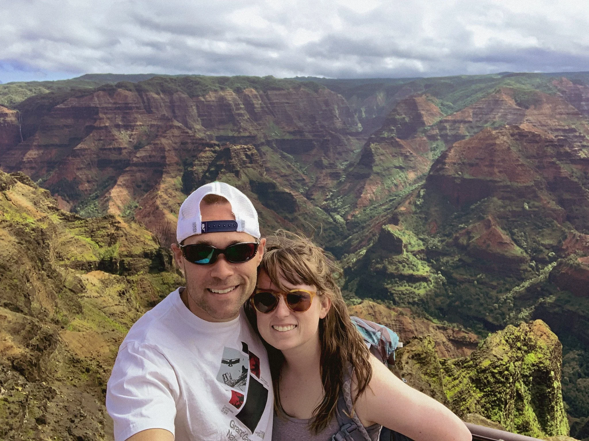 author and husband standing at a lookout over waimea canyon