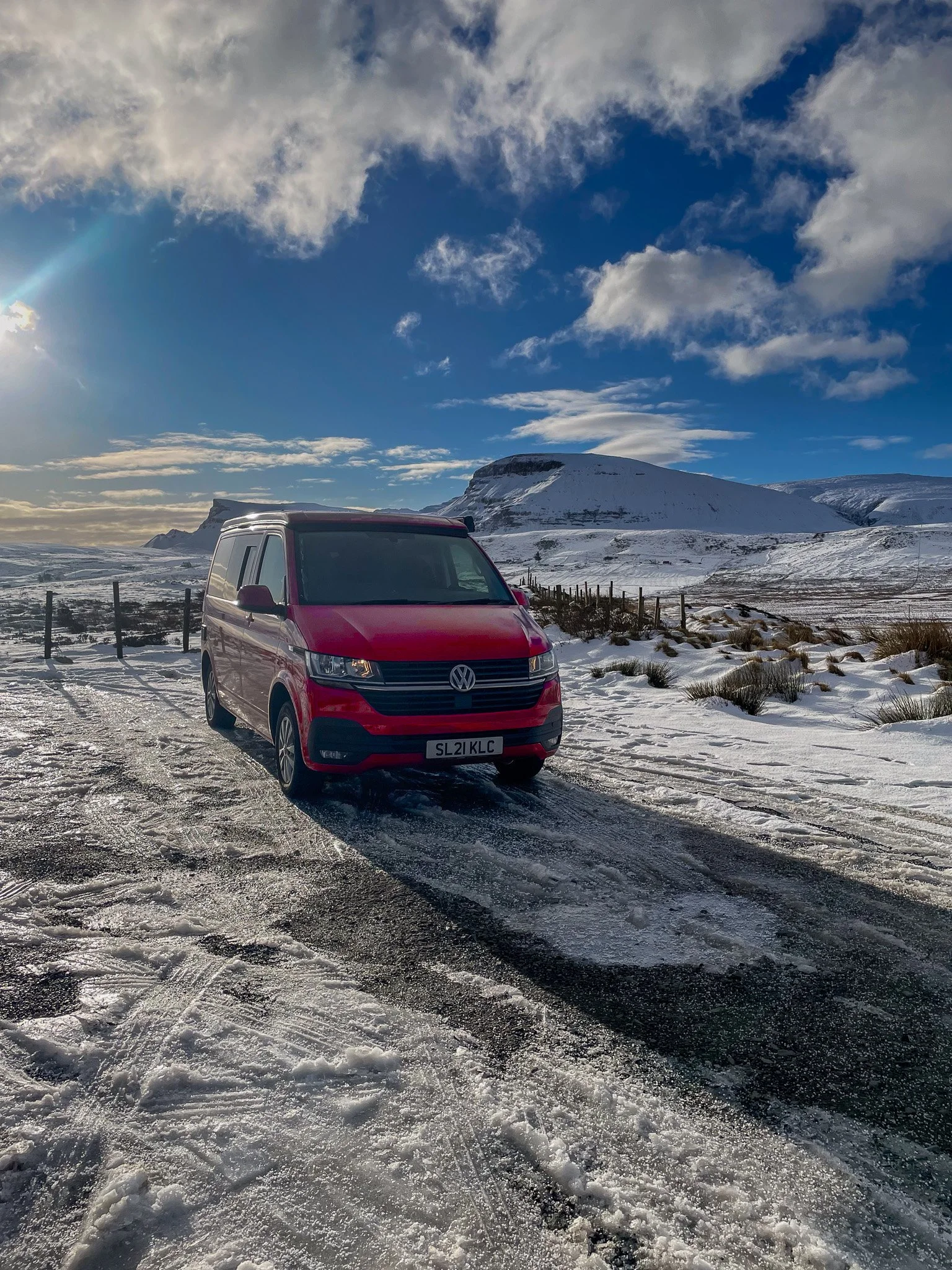 A red campervan parked in a wild camping spot on the Isle of Skye, surrounded by snow