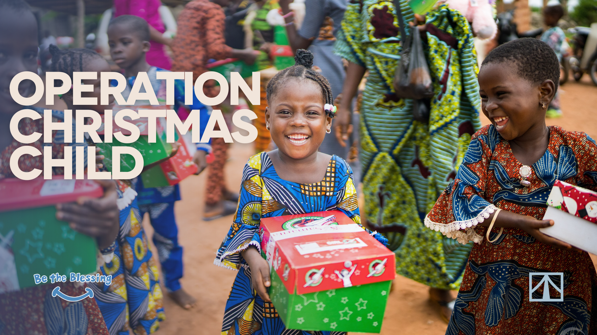 Children in colorful clothing holding wrapped presents and smiling during a donation event, with the main focus on two girls in the foreground.