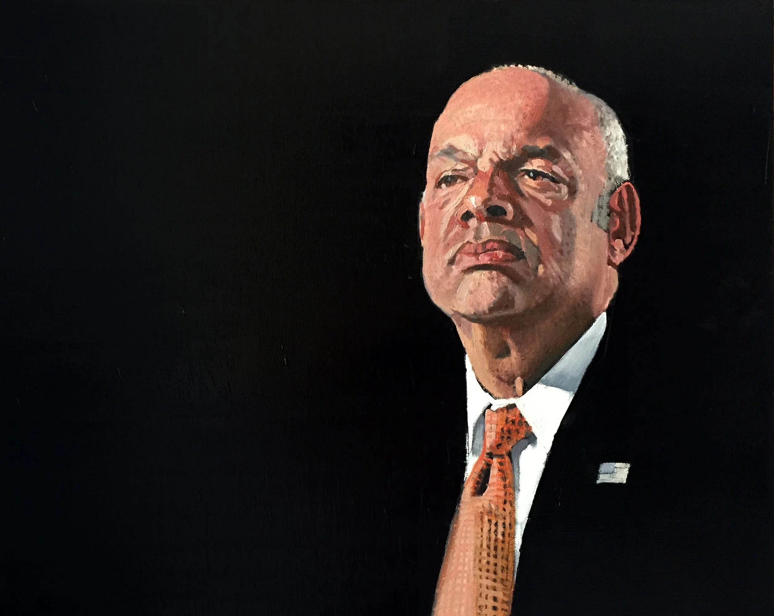 Portrait of an older man with a stern expression, bald head, wearing a dark suit, white shirt, and orange tie, against a black background.