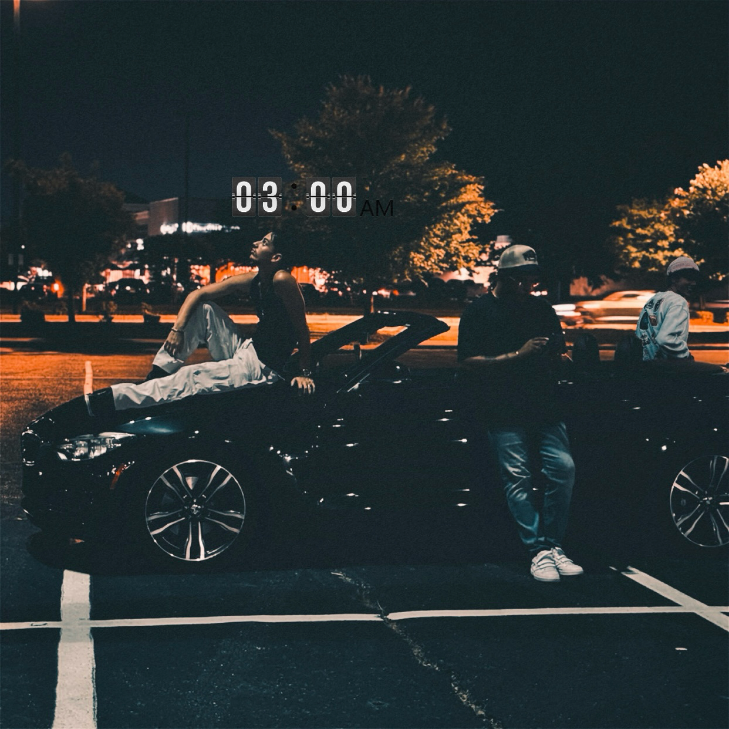 Three young men posing on and around a black sports car at night, with a digital clock showing 03:00 AM in the background, trees, and city lights.