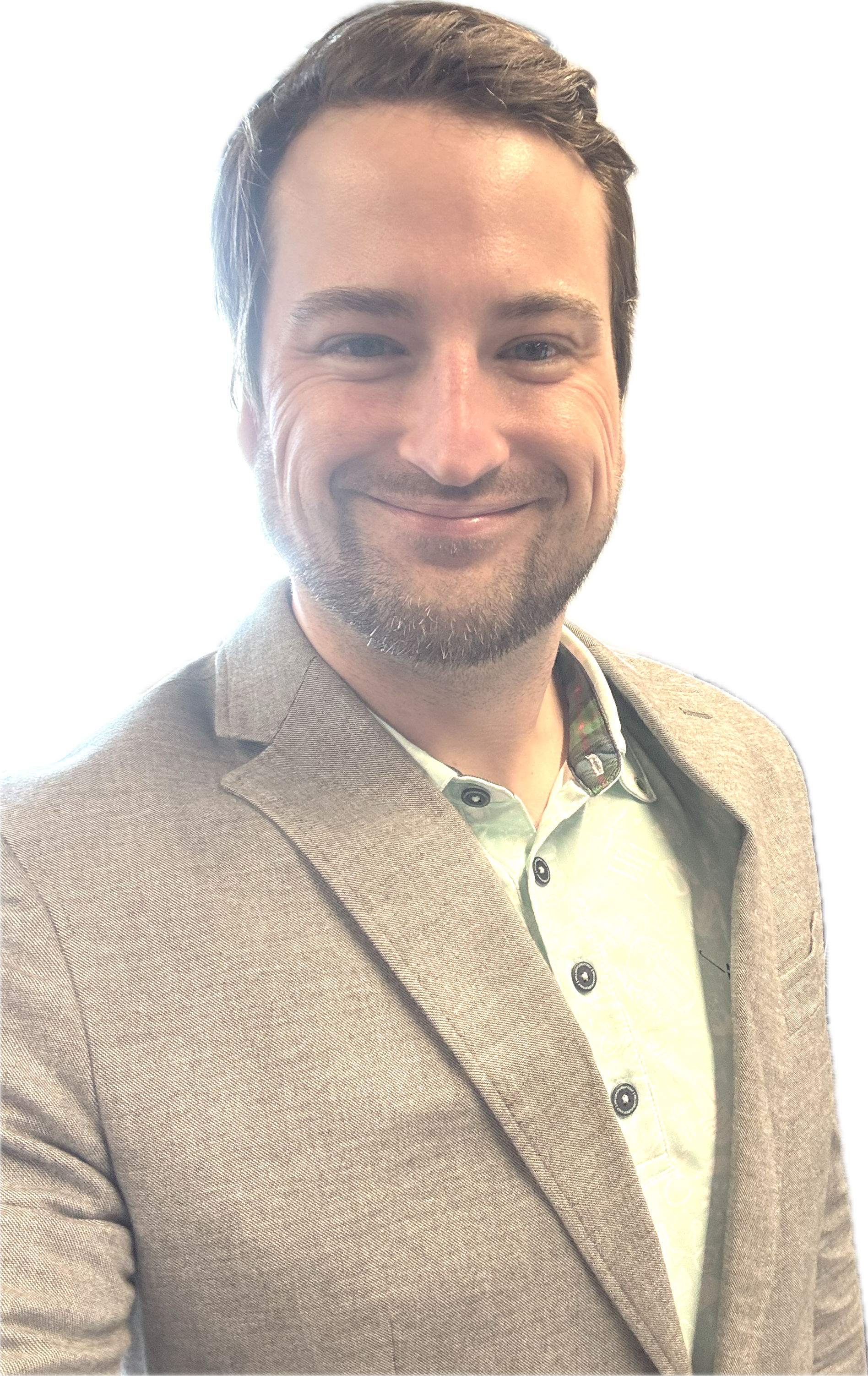 A smiling man with short brown hair and a beard, wearing a light gray blazer over a white shirt with a faint pattern.