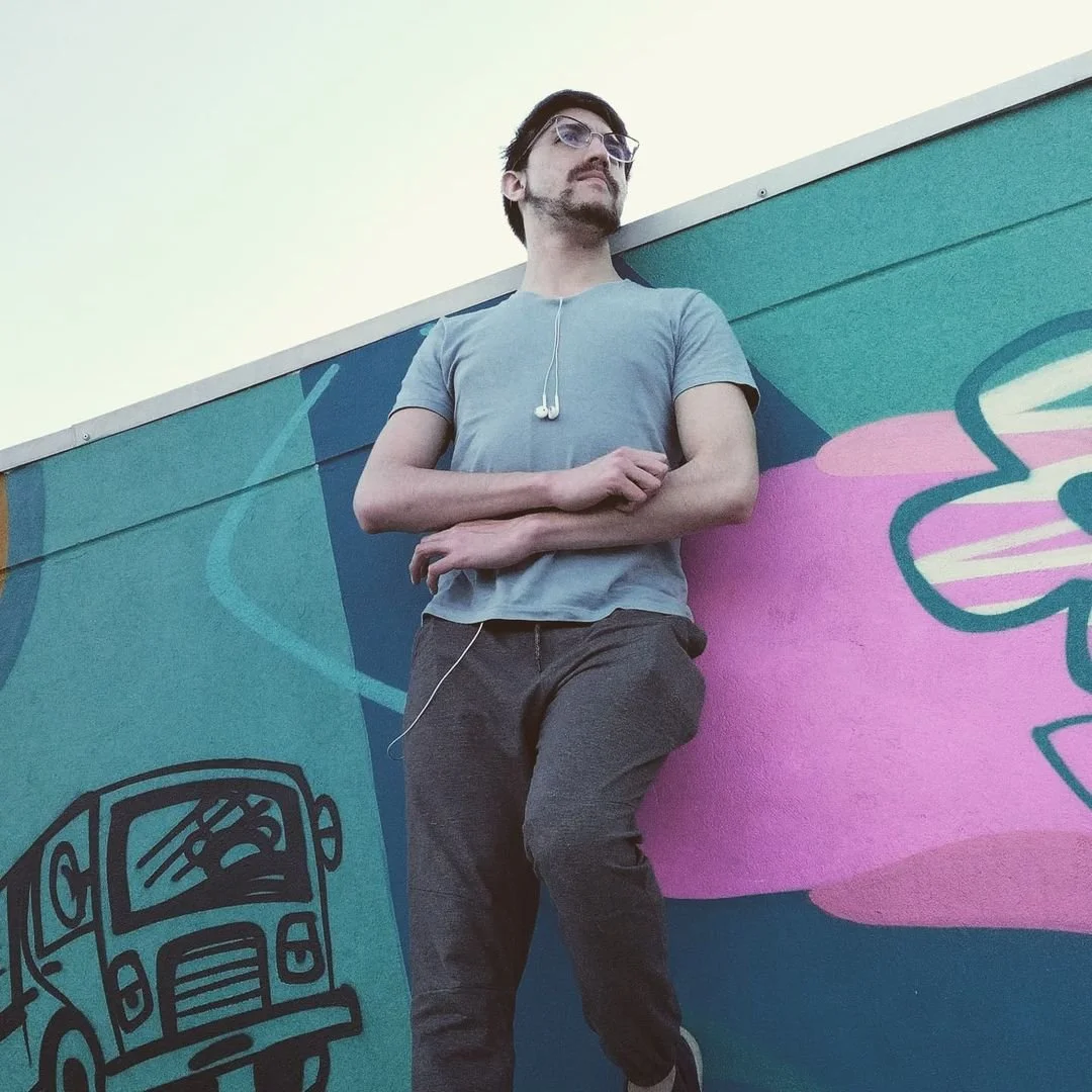 Andrés Uribe, recargado en una pared con graffiti, en un entorno urbano.
