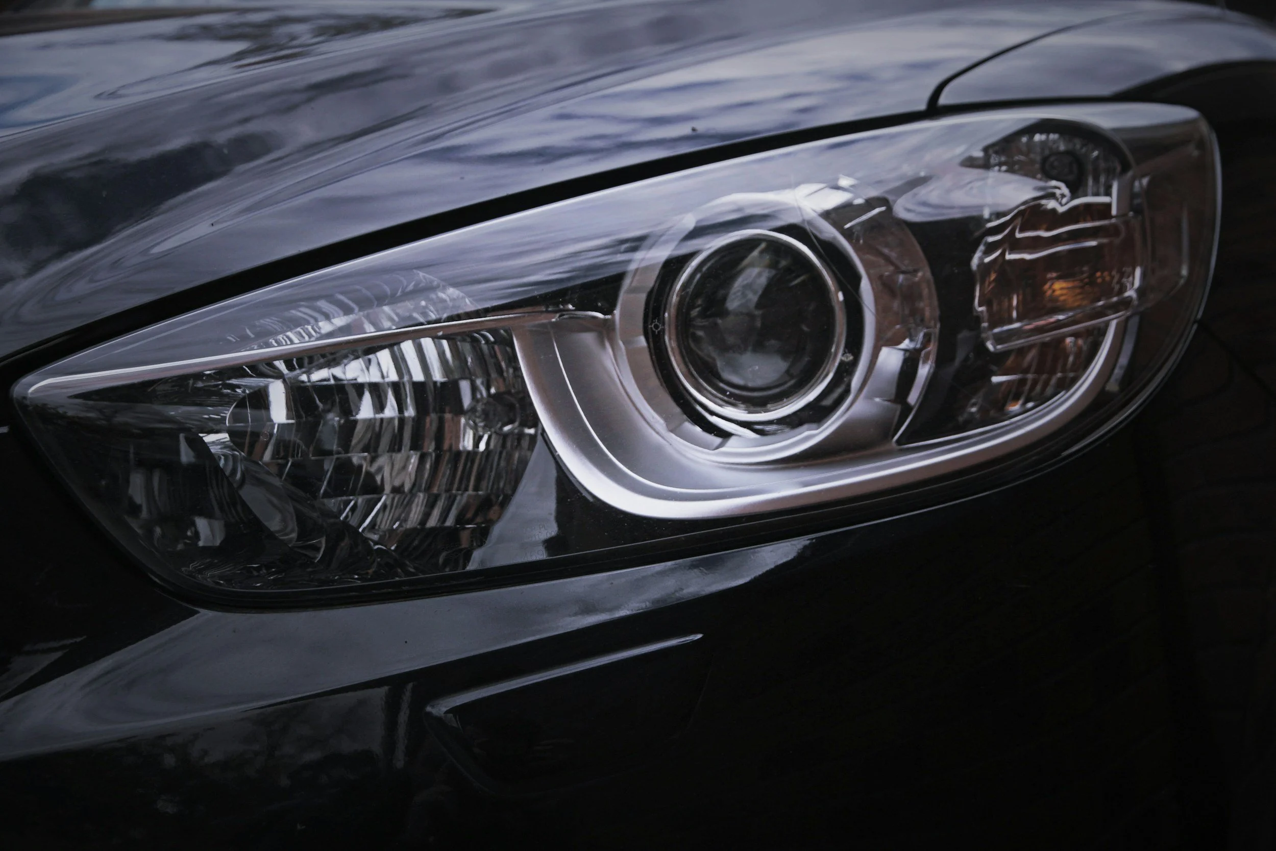 Close-up of a modern car headlight with clear lens and reflective interior.