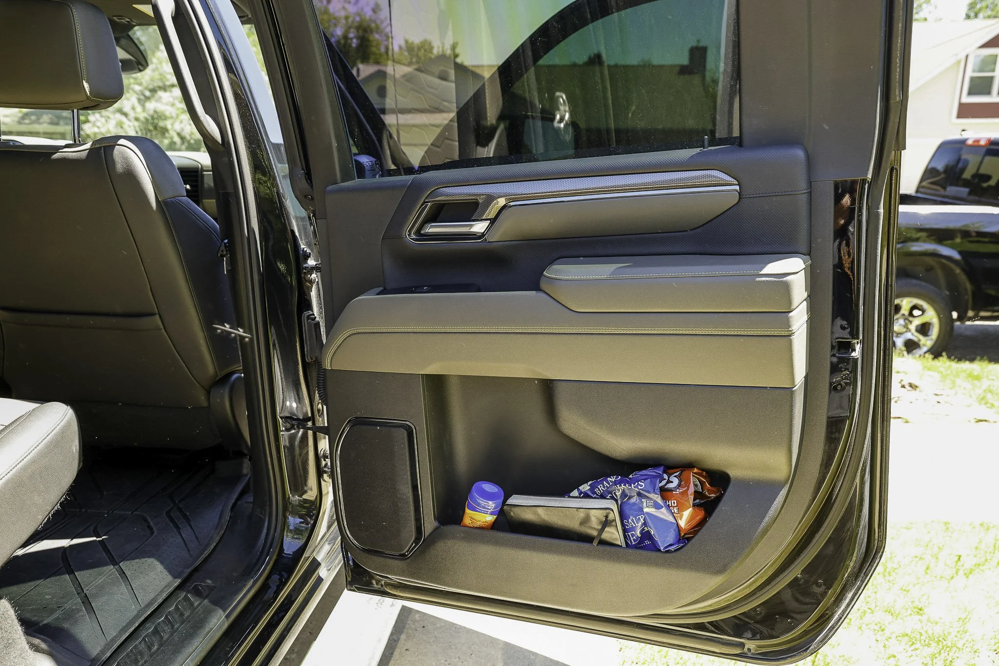 Open car door revealing interior storage pocket with snacks and a bottle.