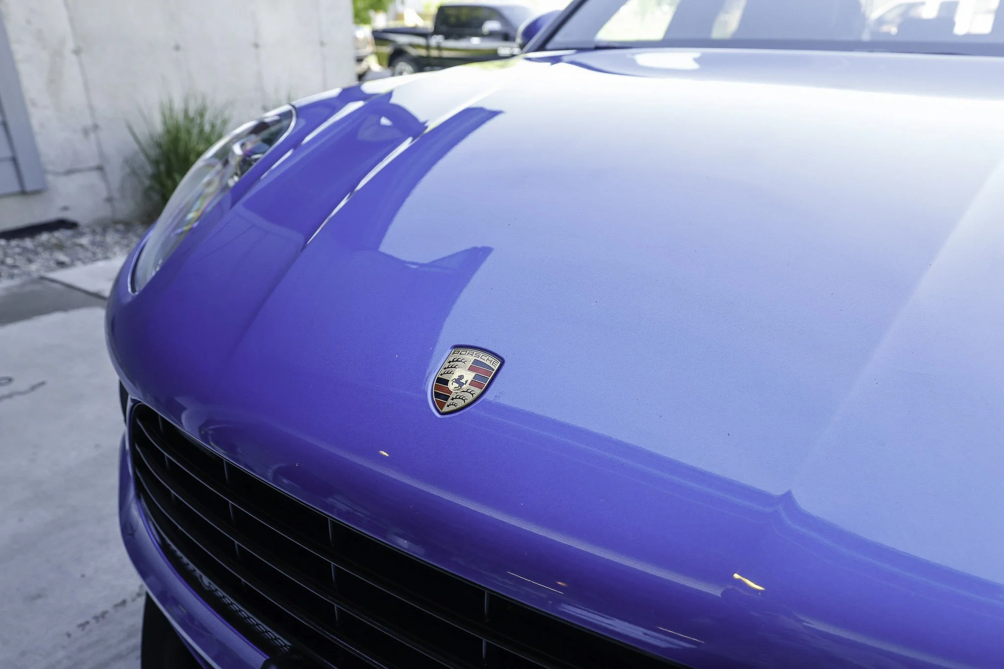 Close-up of the front of a blue Porsche car showing the hood with a Porsche emblem.