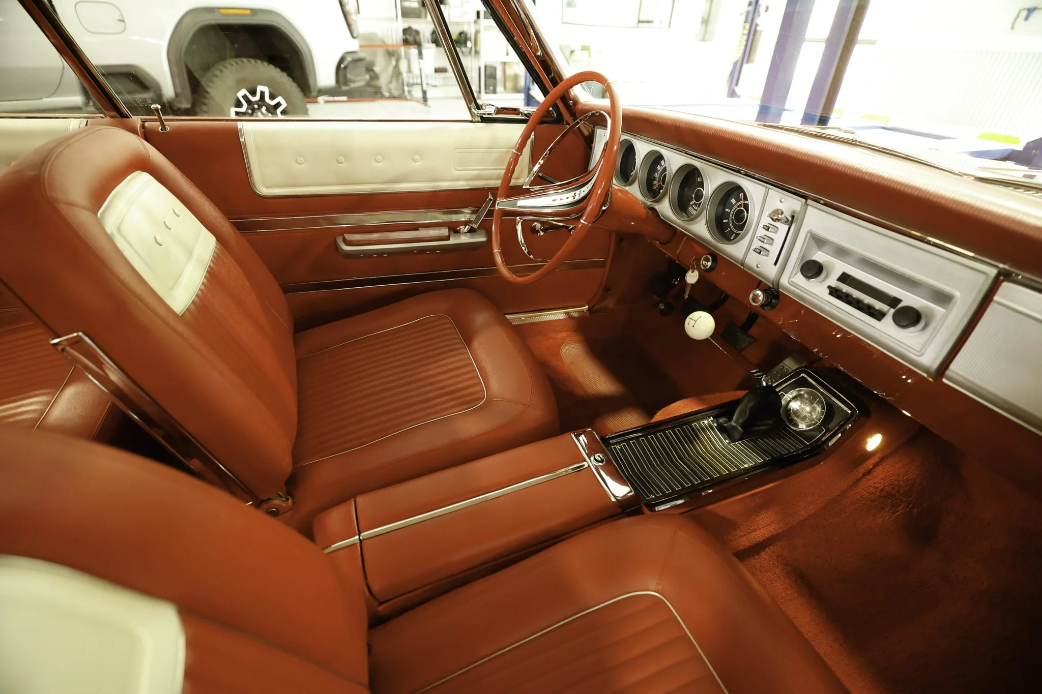 Interior of a vintage red and white car with a manual gear shift, dashboard gauges, red leather seats, and a white gear shift knob.