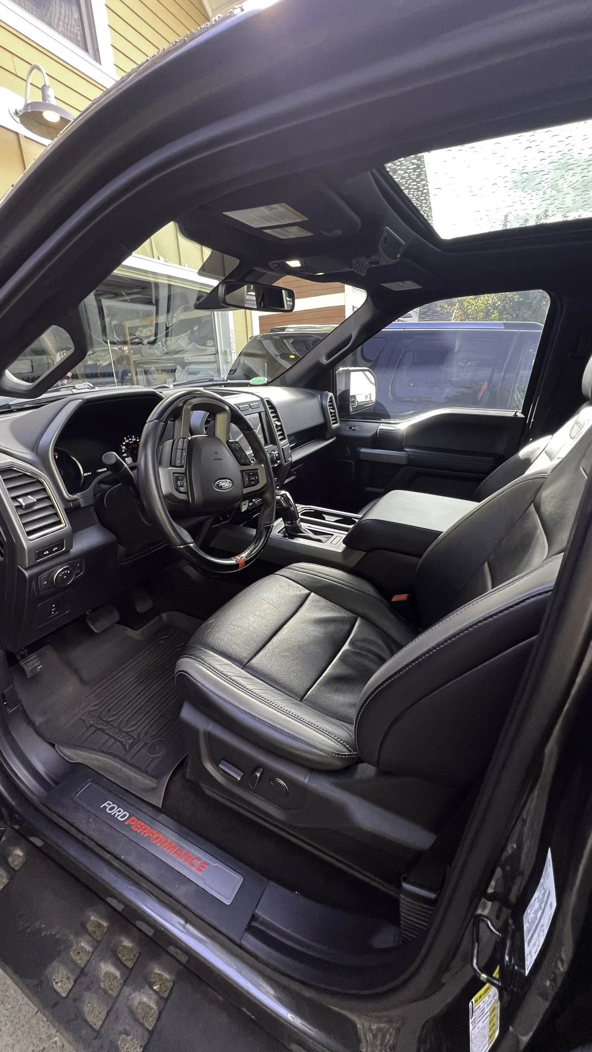 Interior of a black Ford vehicle with leather seats, steering wheel, dashboard, gear shift, and sunroof visible.