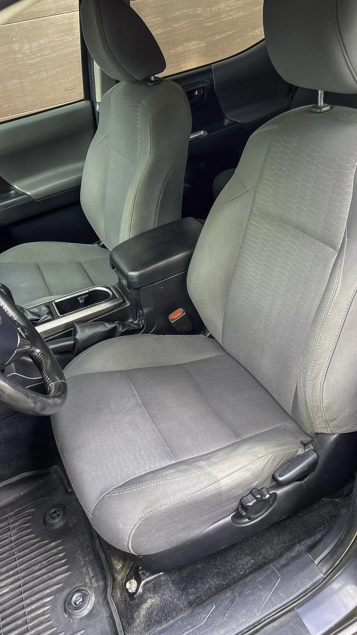 Interior of a car showing the driver's seat, passenger seat, center console, and floor mat.