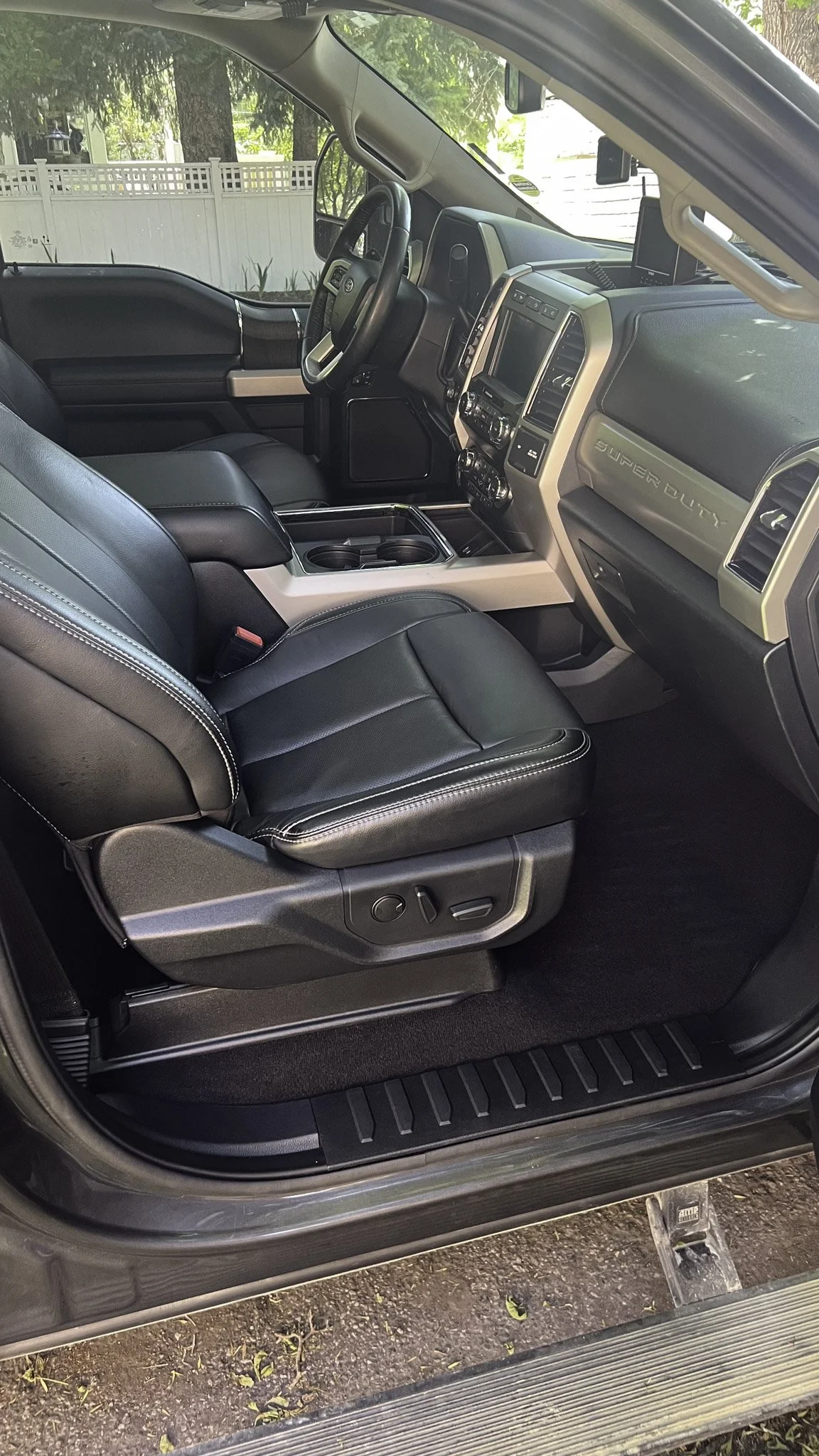 Interior of a modern pickup truck, showing the front driver and passenger seats, dashboard, and center console with cup holders.