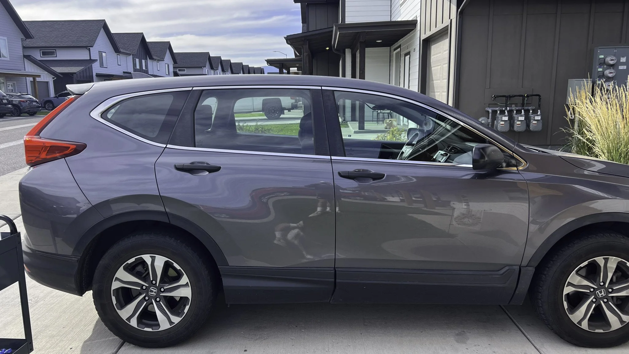 Gray Honda SUV parked outdoors in a residential area with modern houses in the background.