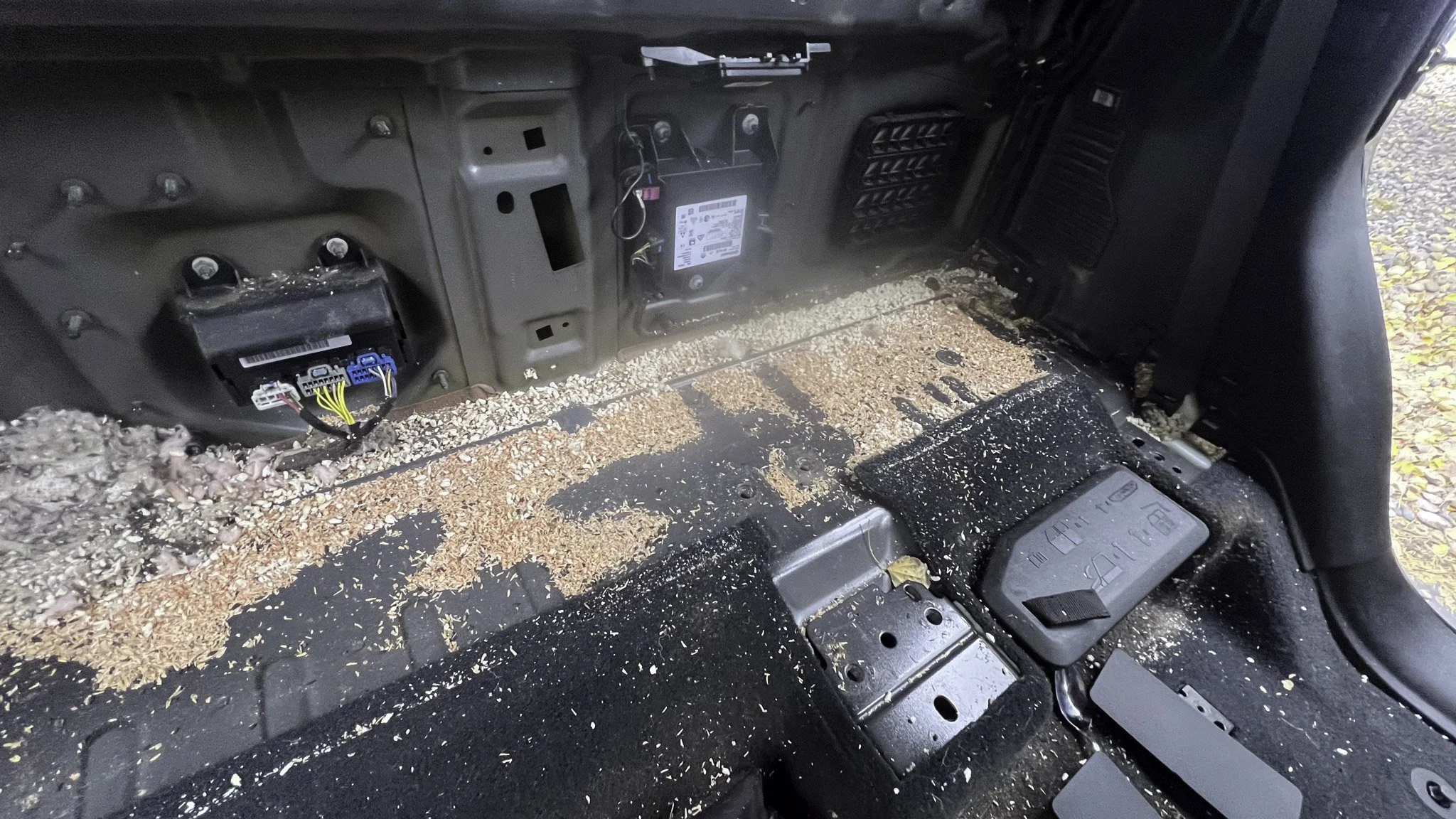 Interior of a vehicle's dashboard area with exposed wiring, dust, and debris.