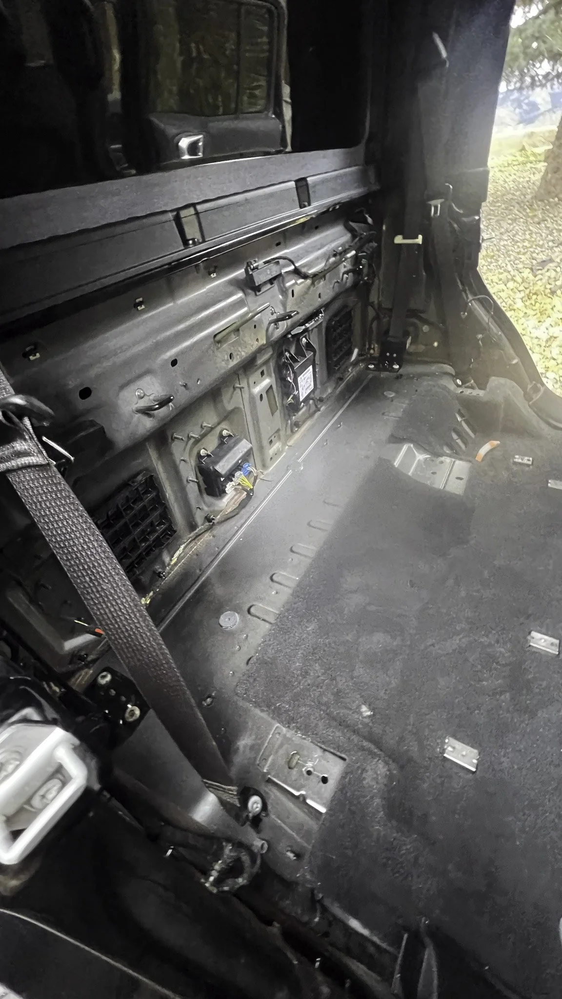 Interior of a vehicle with the dashboard removed, revealing metal framework, wiring, and some electronic components.