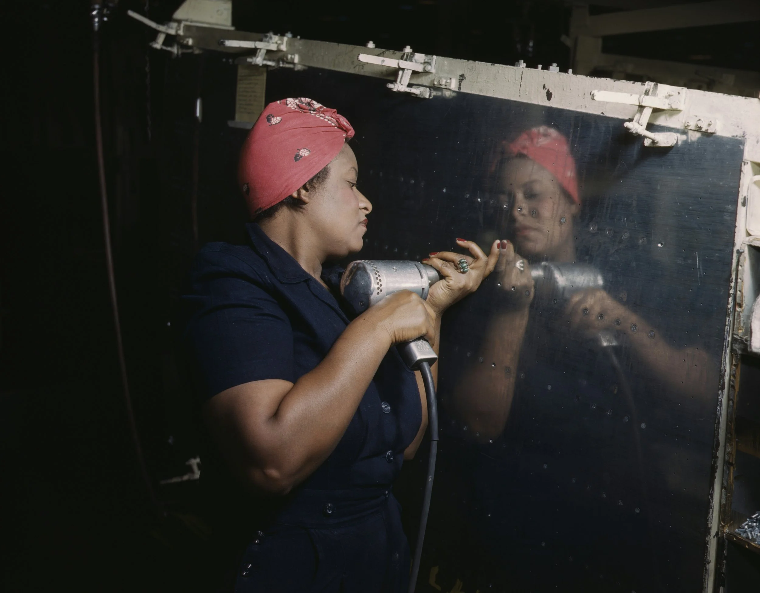 A woman dressed similar to Rosie the Riveter who's doing industrial work