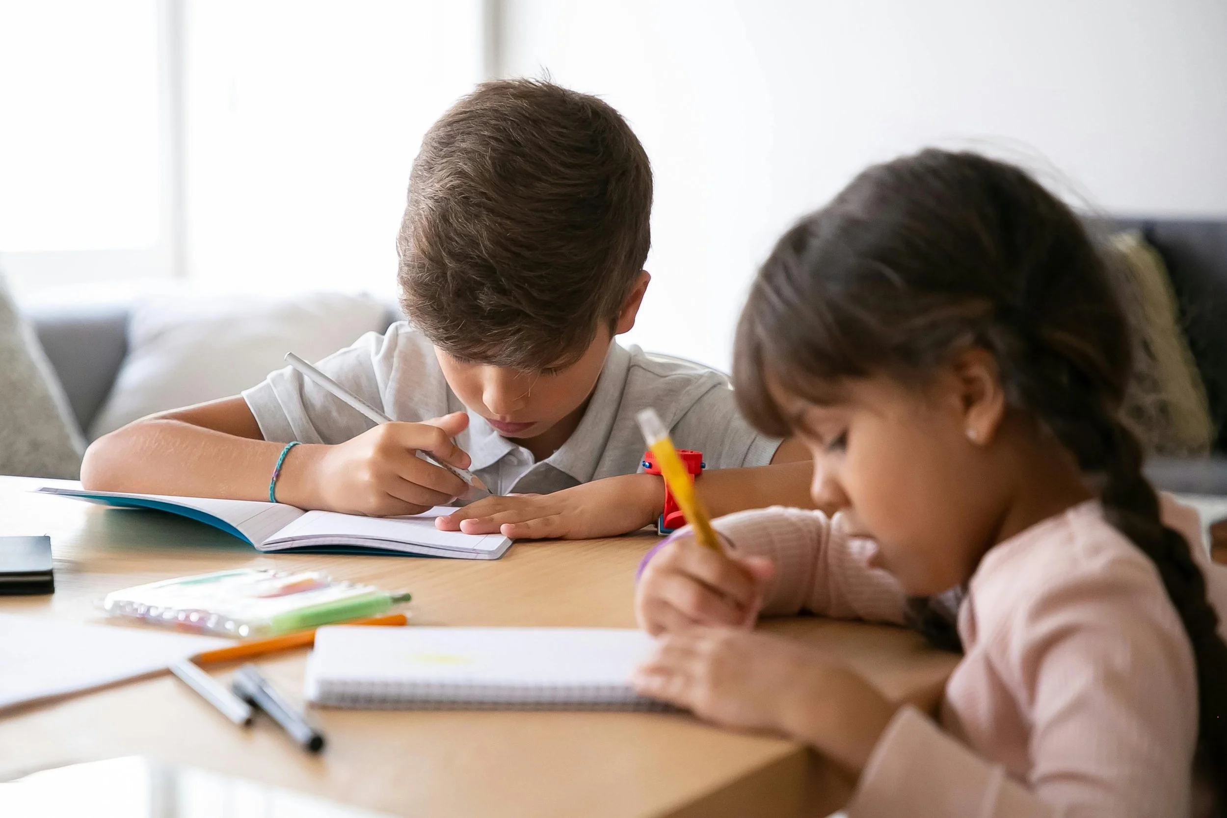 Two children writing at a kitchen table