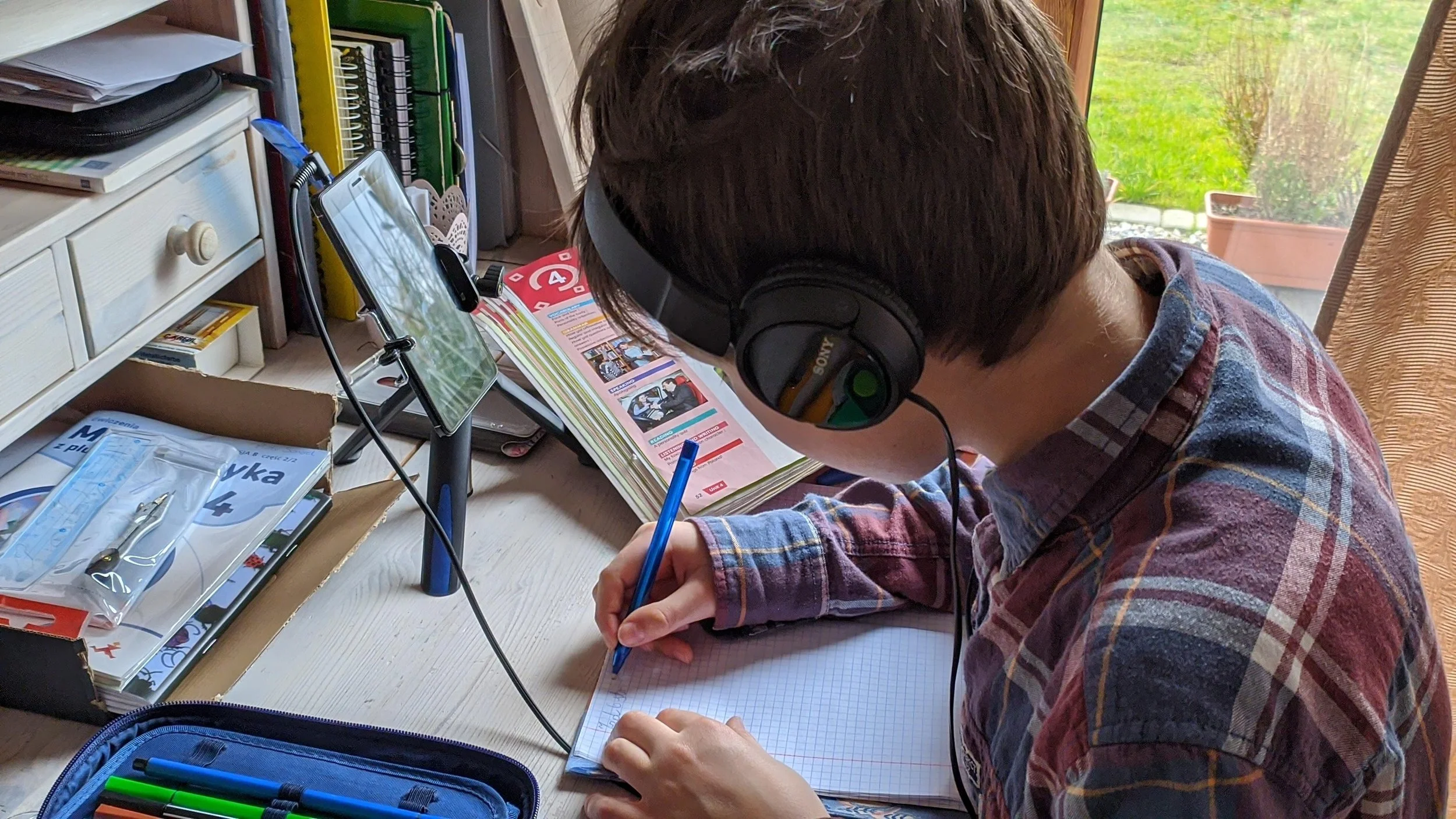 A student works from their phone with headphones on