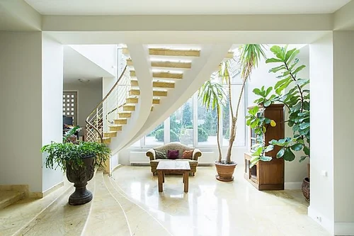 Bright living room with plants and a wooden staircase