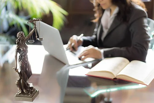 Woman at a desk with a statue of Lady Justice
