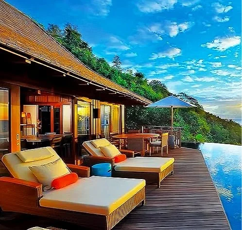 Luxury outdoor patio with lounge chairs, umbrella, and scenic mountain view