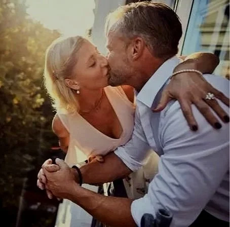 A woman and a man sharing a kiss outdoors during sunset.