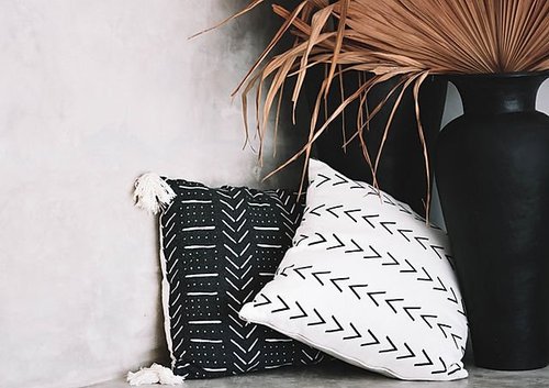 Patterned pillows and a vase with dried palm leaves