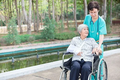 Nurse helping an elderly woman outdoors