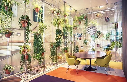 Green chairs around a wooden table with hanging plants