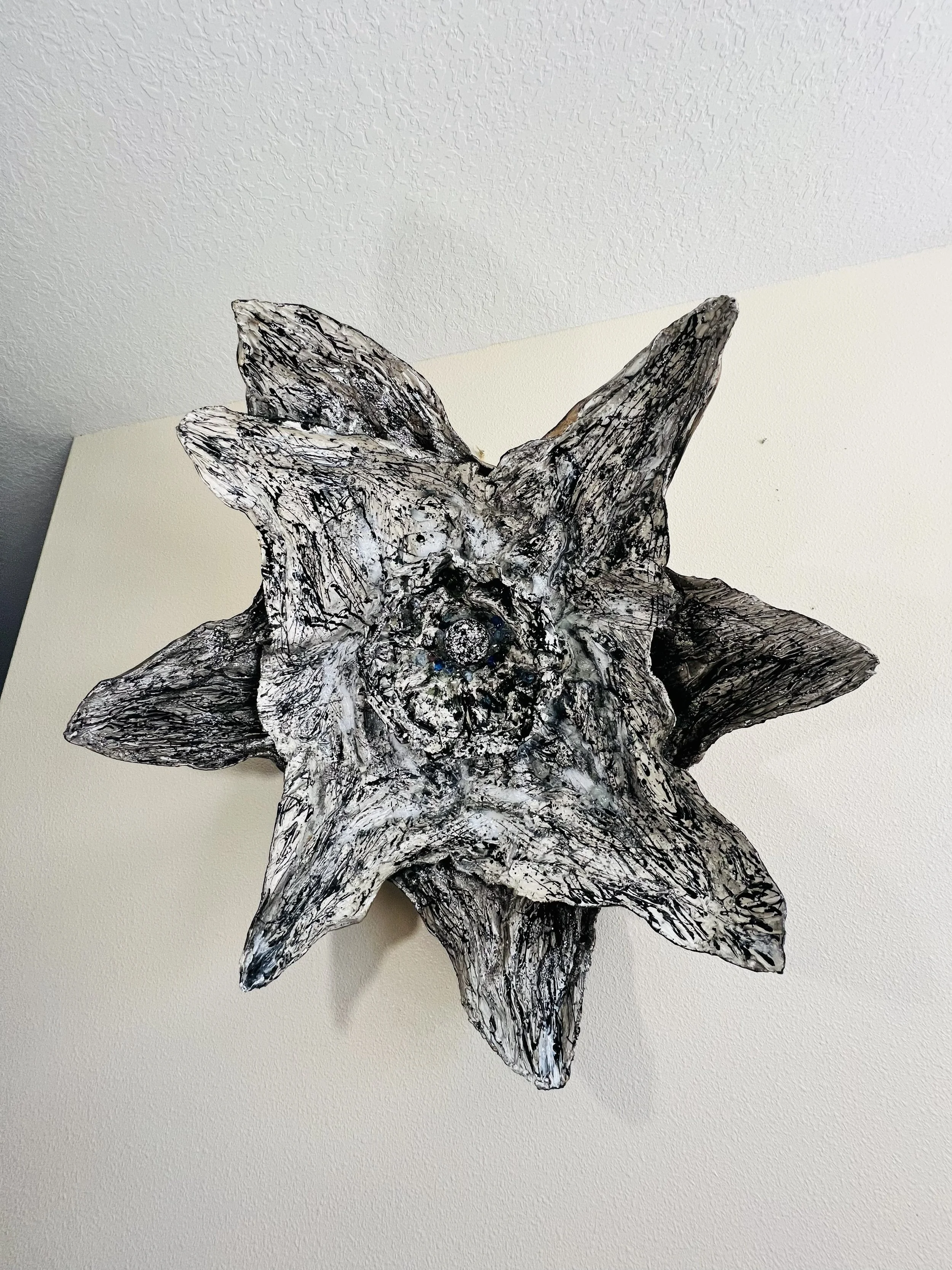 A wooden sculpture resembling a wolf with detailed textured fur and prominent ears, mounted on a wall.