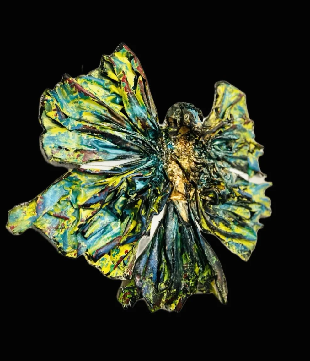 Colorful glass butterfly sculpture with yellow, blue, green, and red hues on black background.