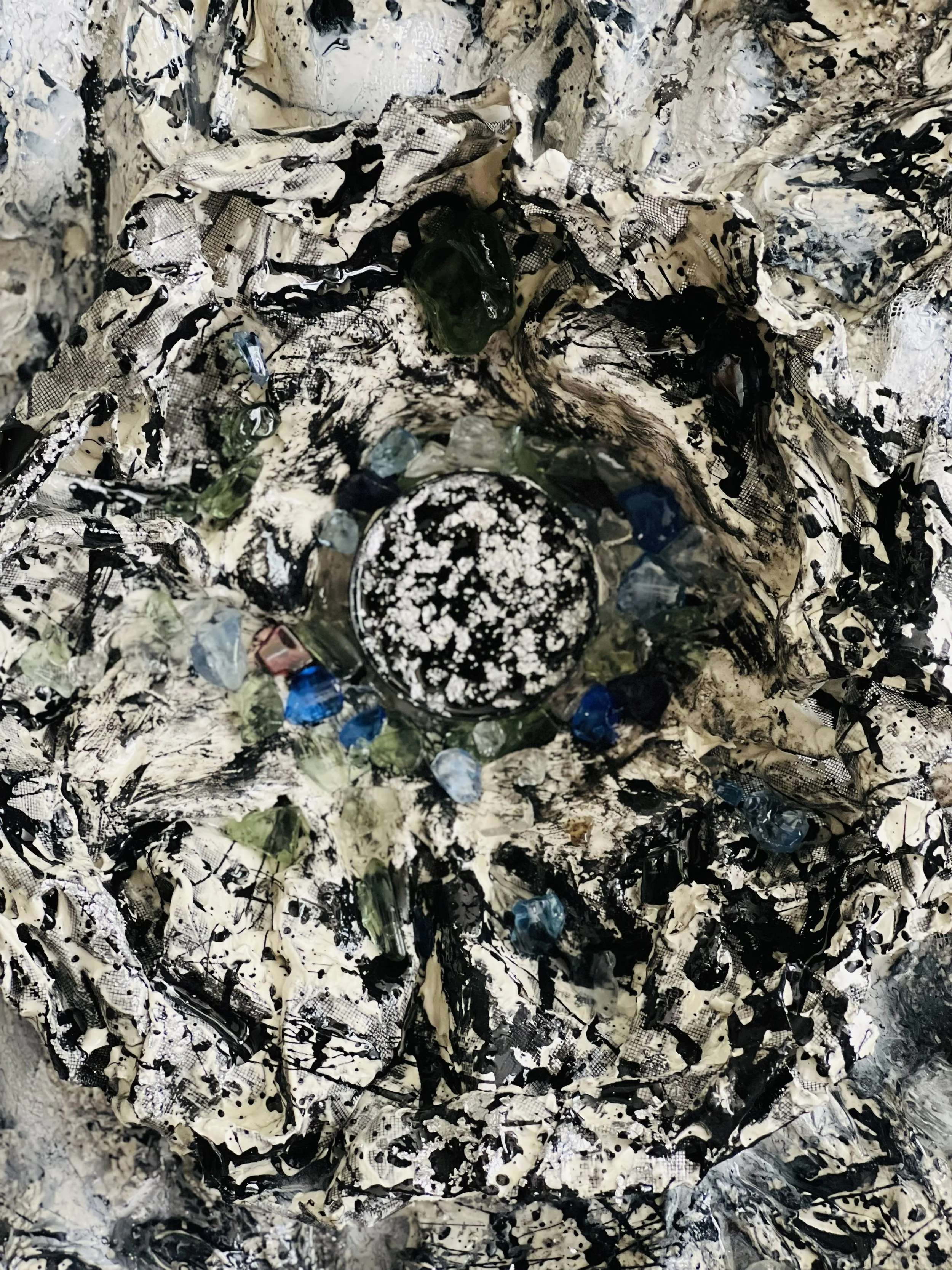 Mixed media art piece with a central round shape. Wall Installation: A sculptural focal point that brings dimension and impact to tall walls and architectural features.