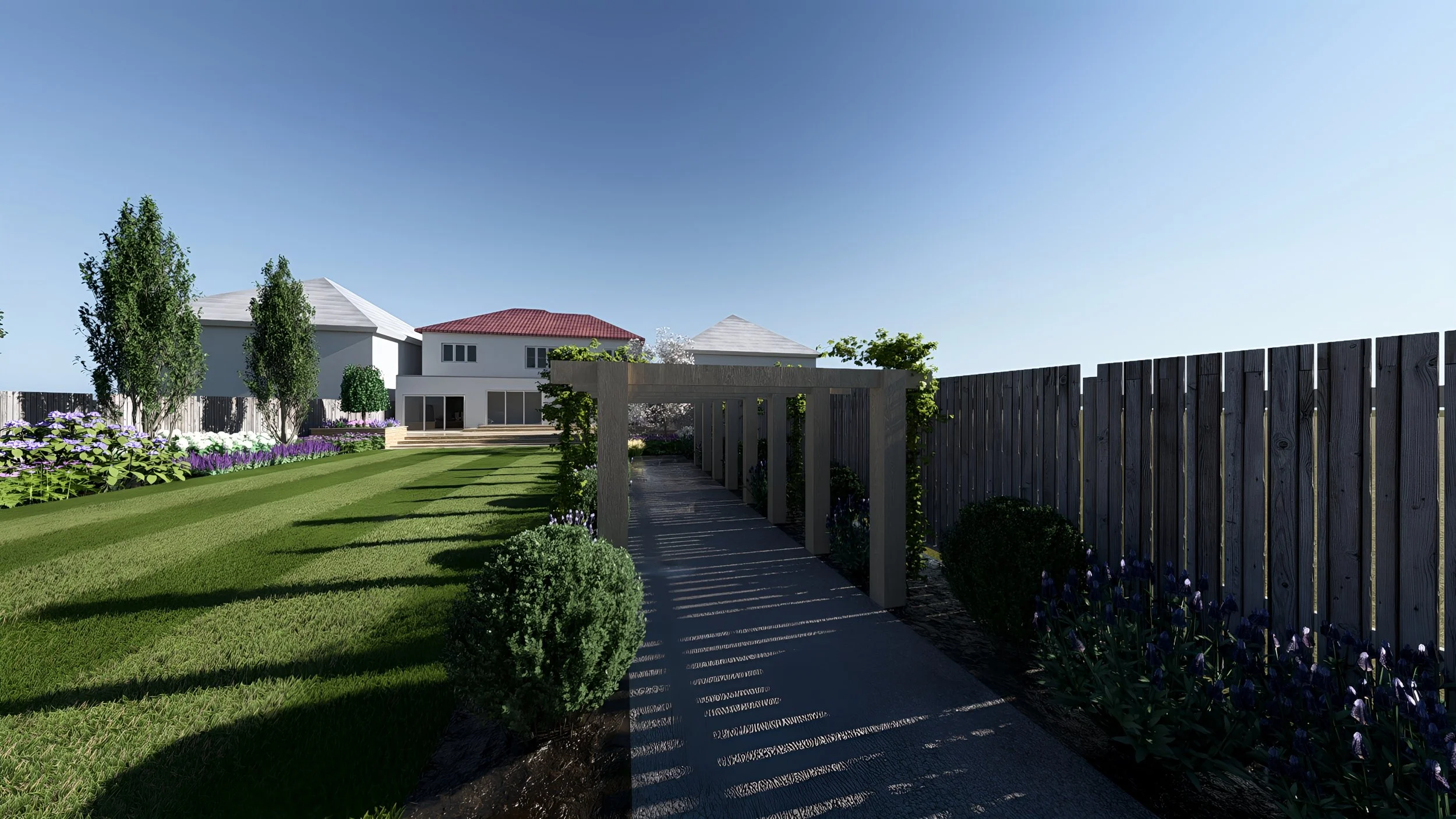 A backyard with a dark wooden fence, a shaded walkway with pergola, green bushes, and a garden with purple and white flowers, and two-story houses with trees in the background.