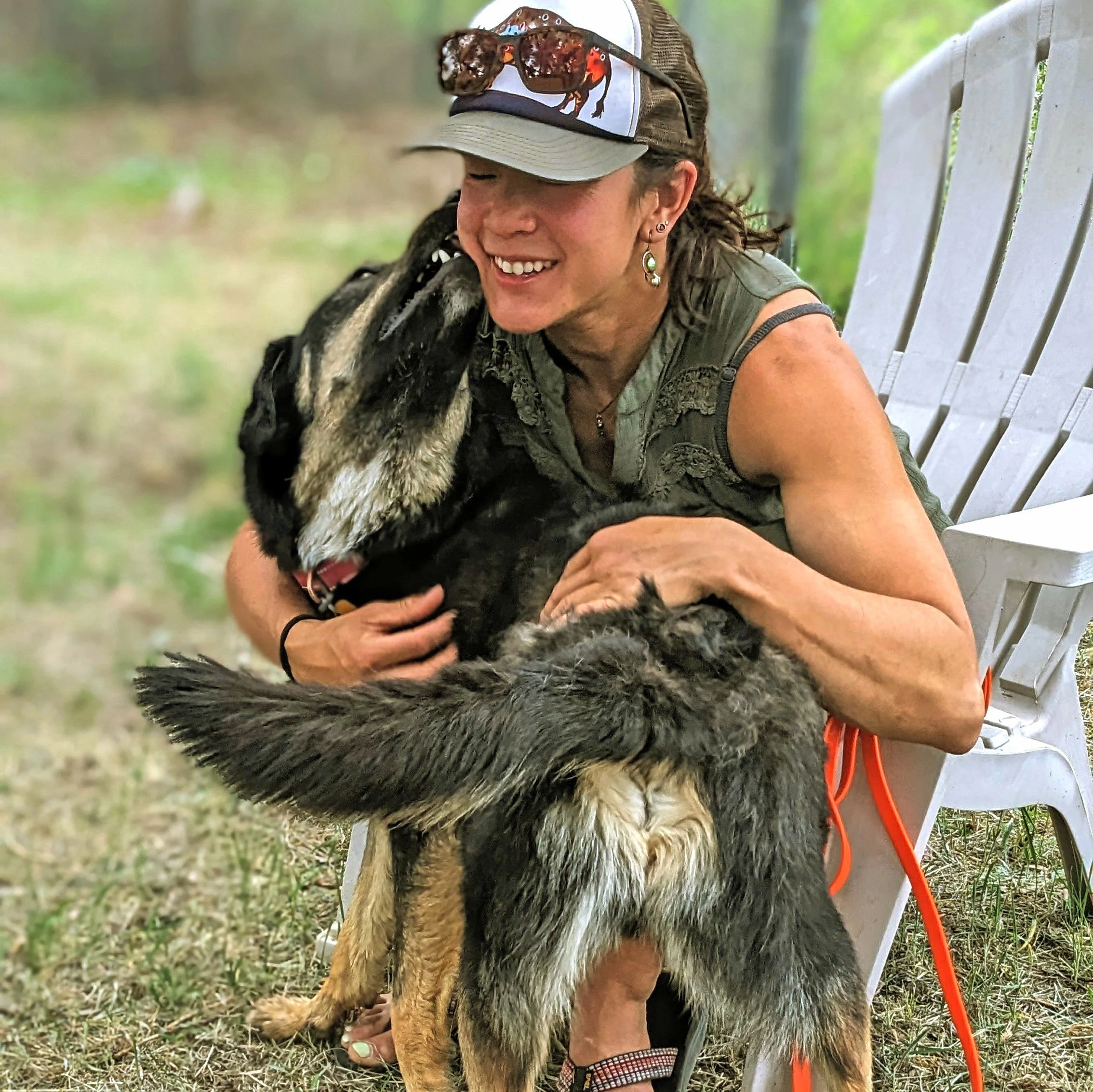 A woman smiling and hugging a large dog as it nuzzles her face after making a pet adoption in Ridgway.