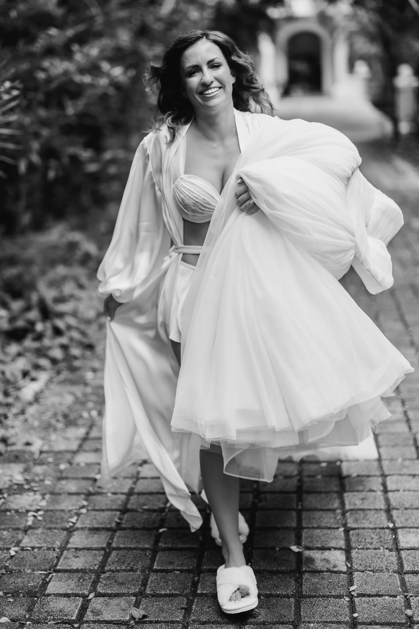 Black and White photo of Bride Running with Wedding Dress Detail Photo.