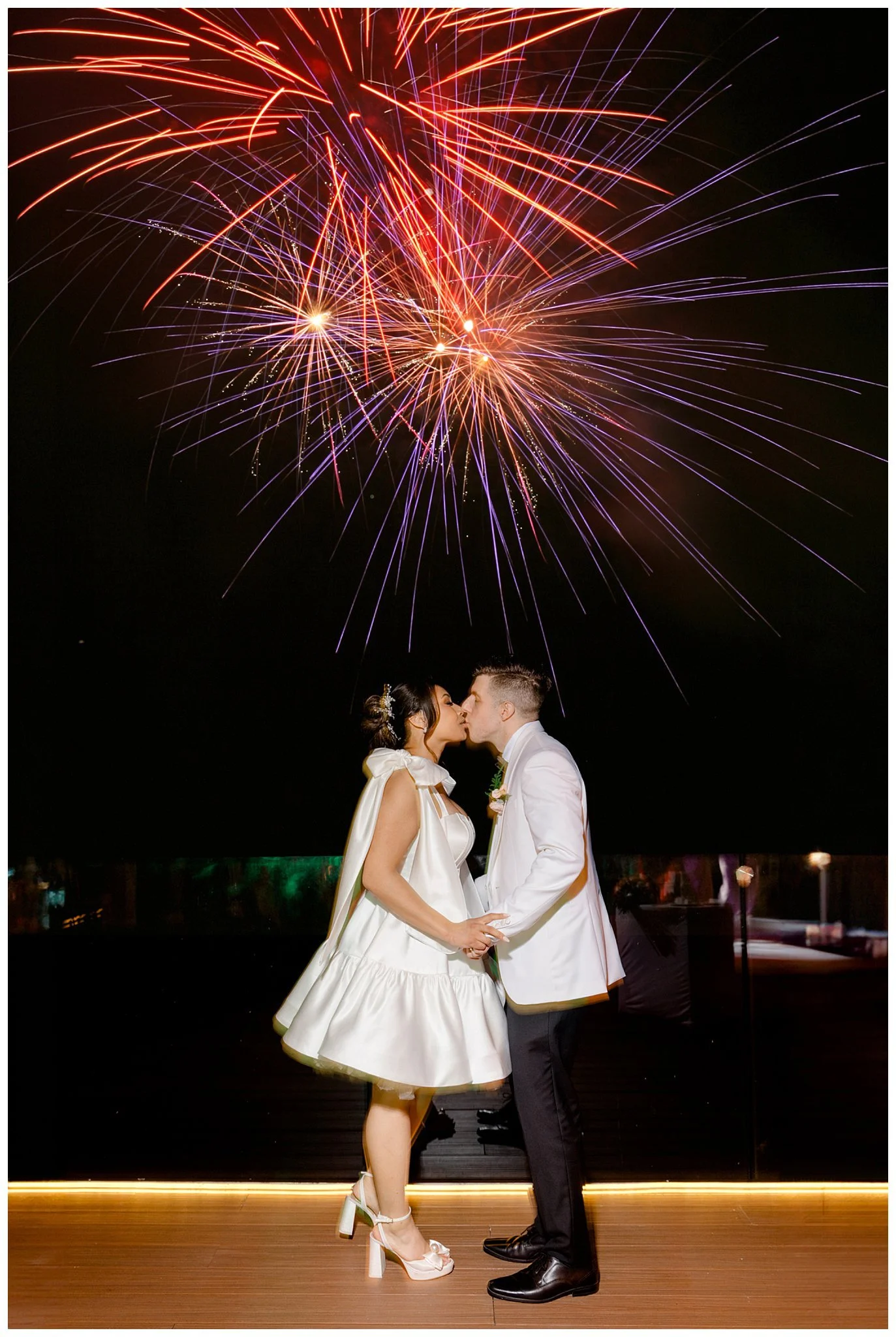 Nighttime wedding kiss during fireworks reception lighting at Dreams Bahia Mita