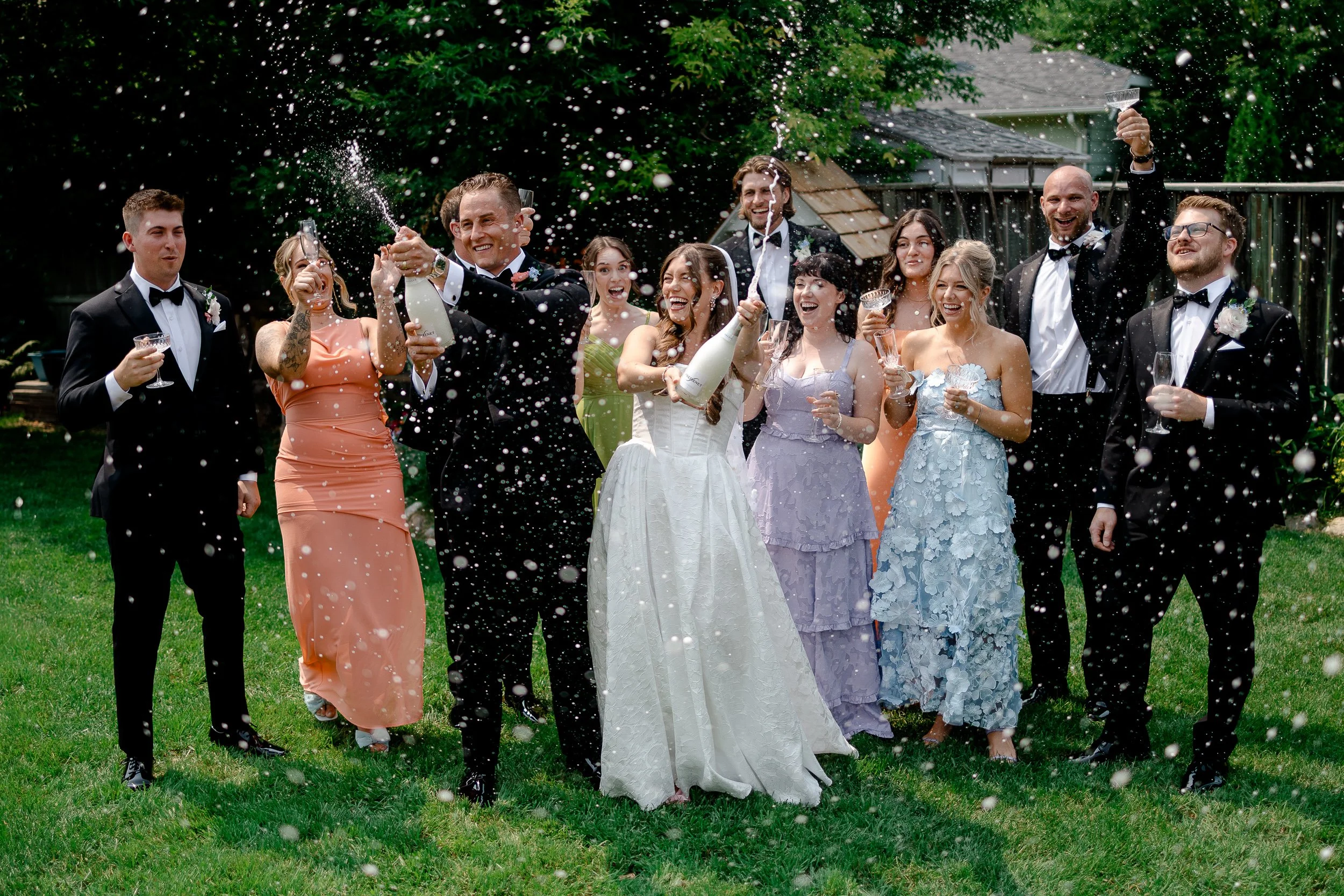 Wedding Party Spraying Champagne Celebrating Colourful Garden