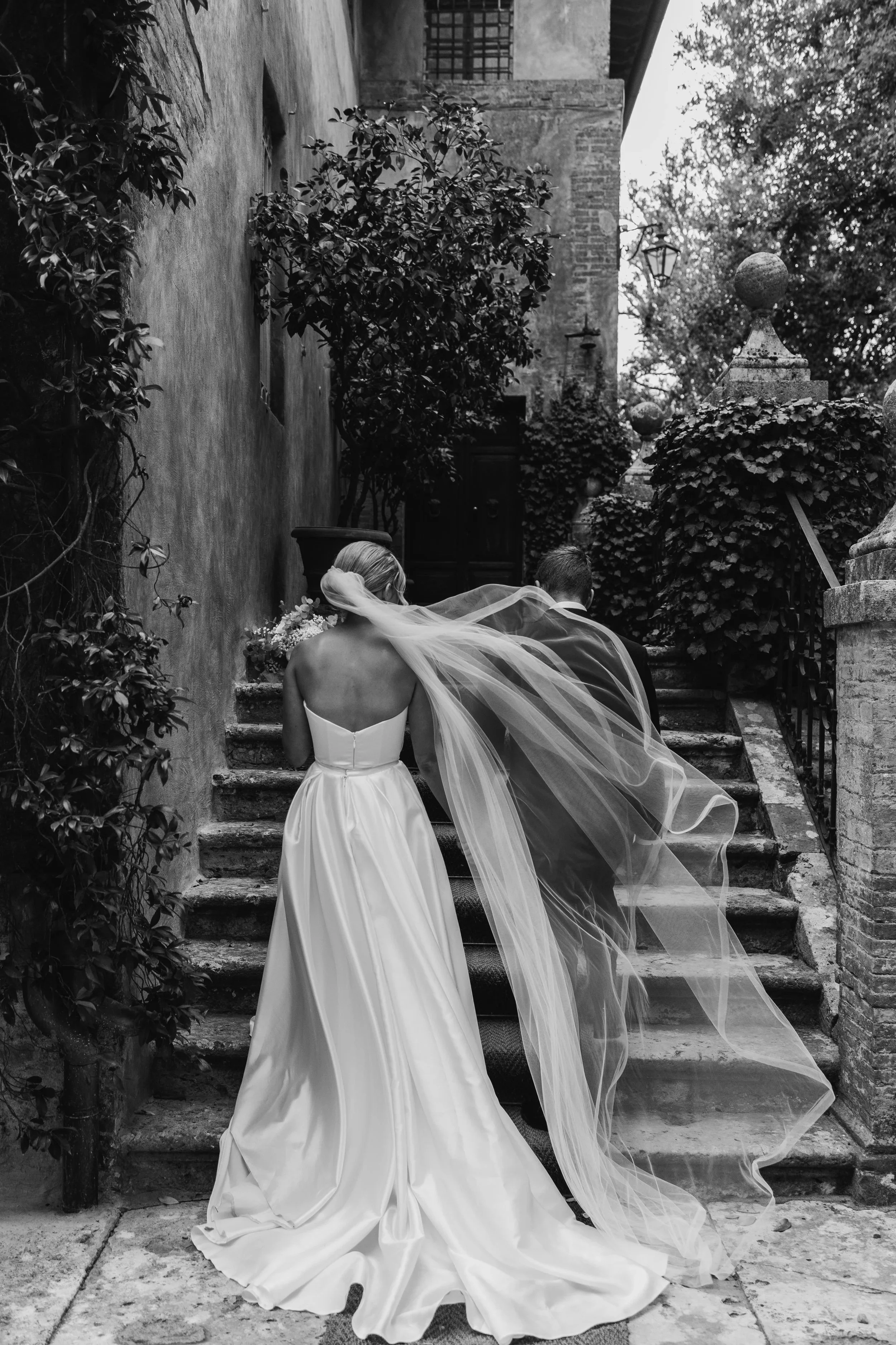 Bride and groom walk holding hands up the stairs in Tuscany Italy.