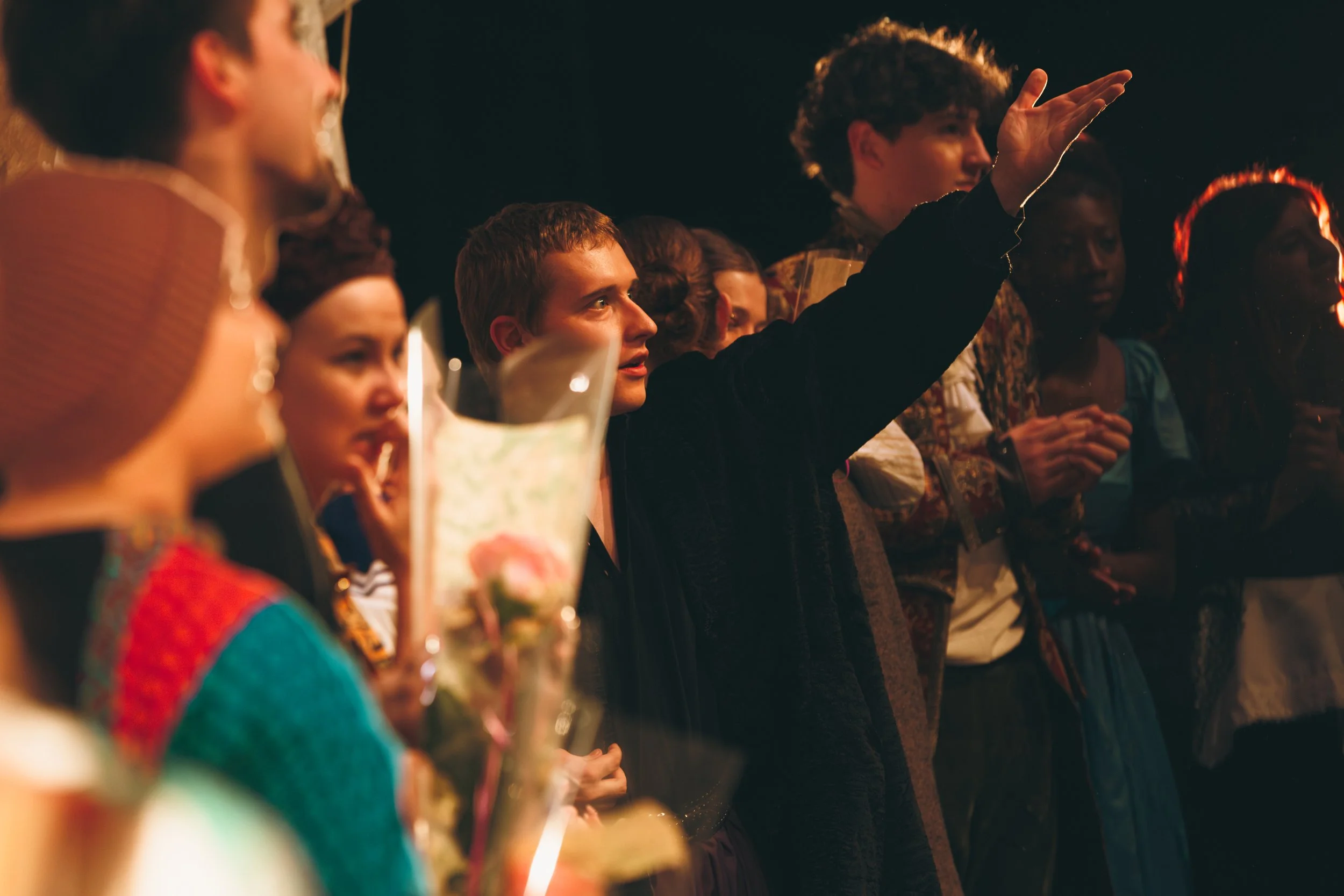Groupe de personnes au théâtre ou au cinéma, dont une personne au centre fait un geste de main en parlant ou en répondant à une question.