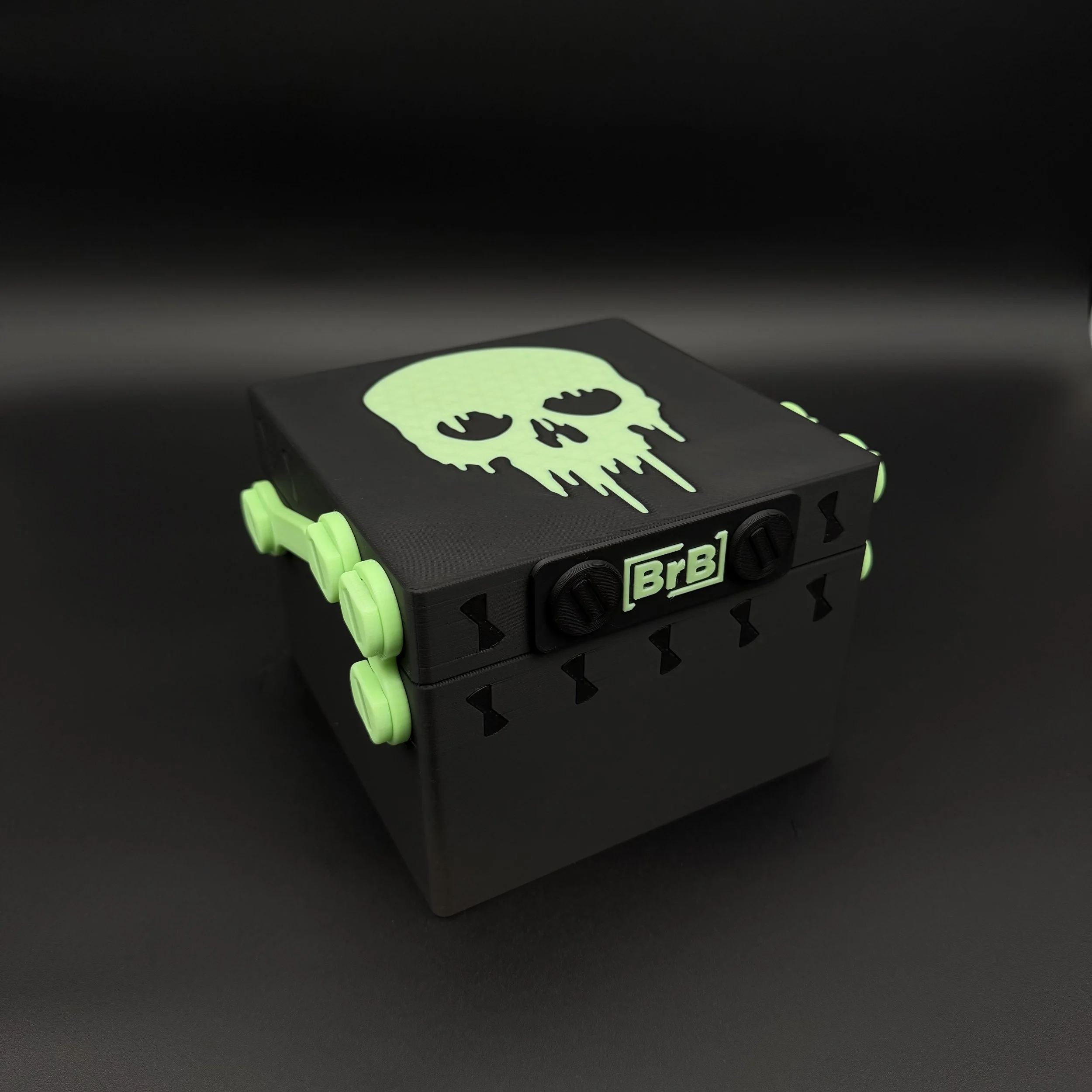A black deck box with a green dripping skull on the lid and green hardware.