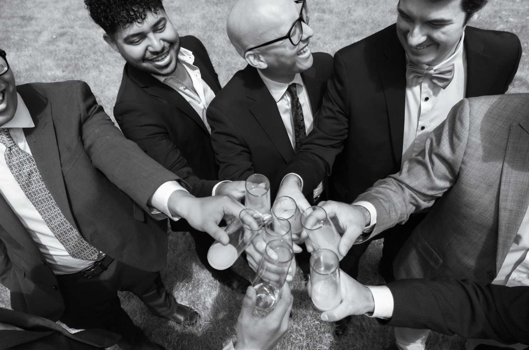 Group of men in suits raising glasses for a toast, celebrating together outdoors.