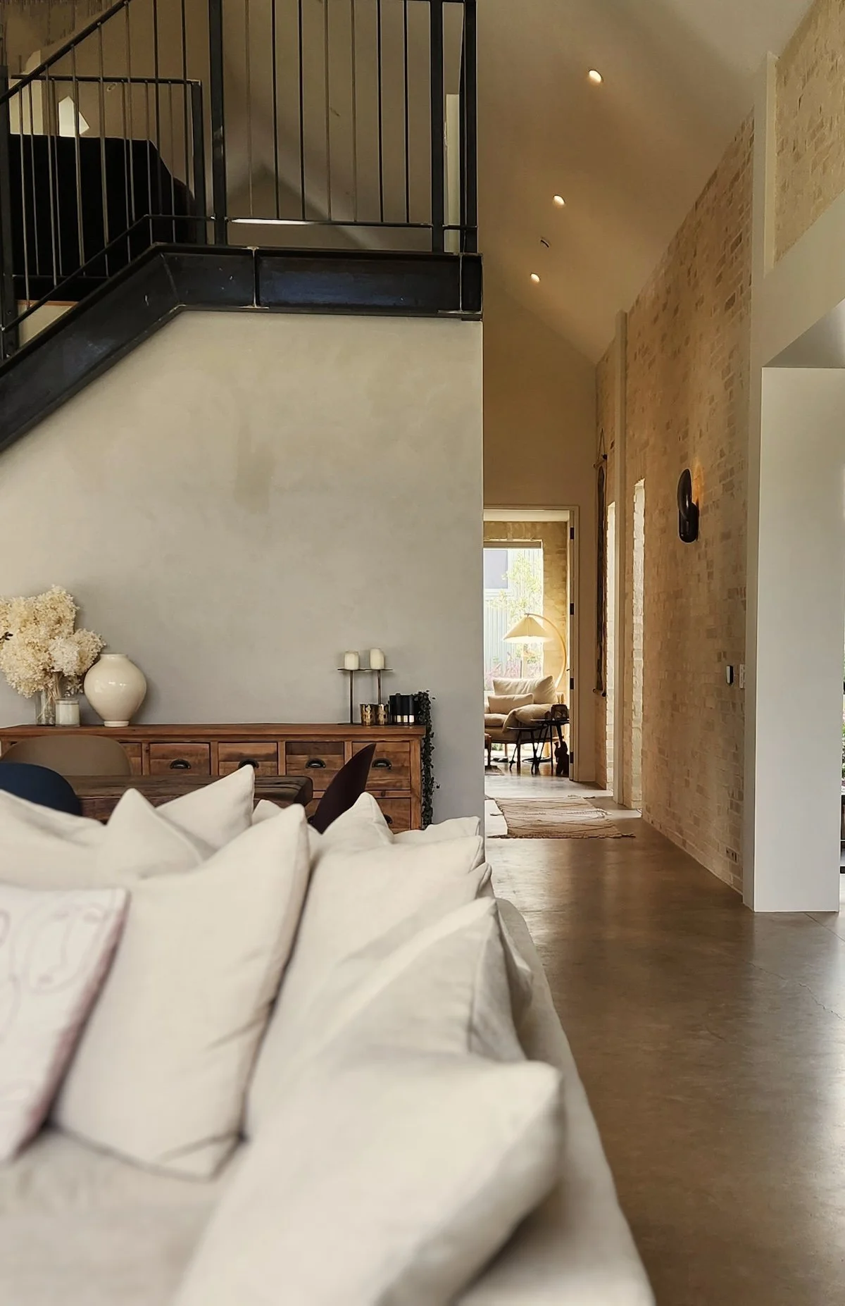 A beautifully styled living area looking towards a long sun bathed hallway.